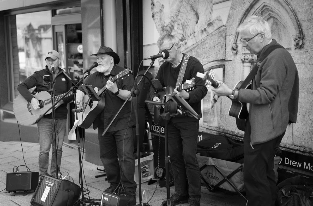 Group of older buskers performing in Banbridge Buskfest photographed in mono.