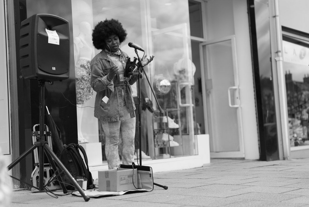 Dark skinned singer performing beside a large speaker.