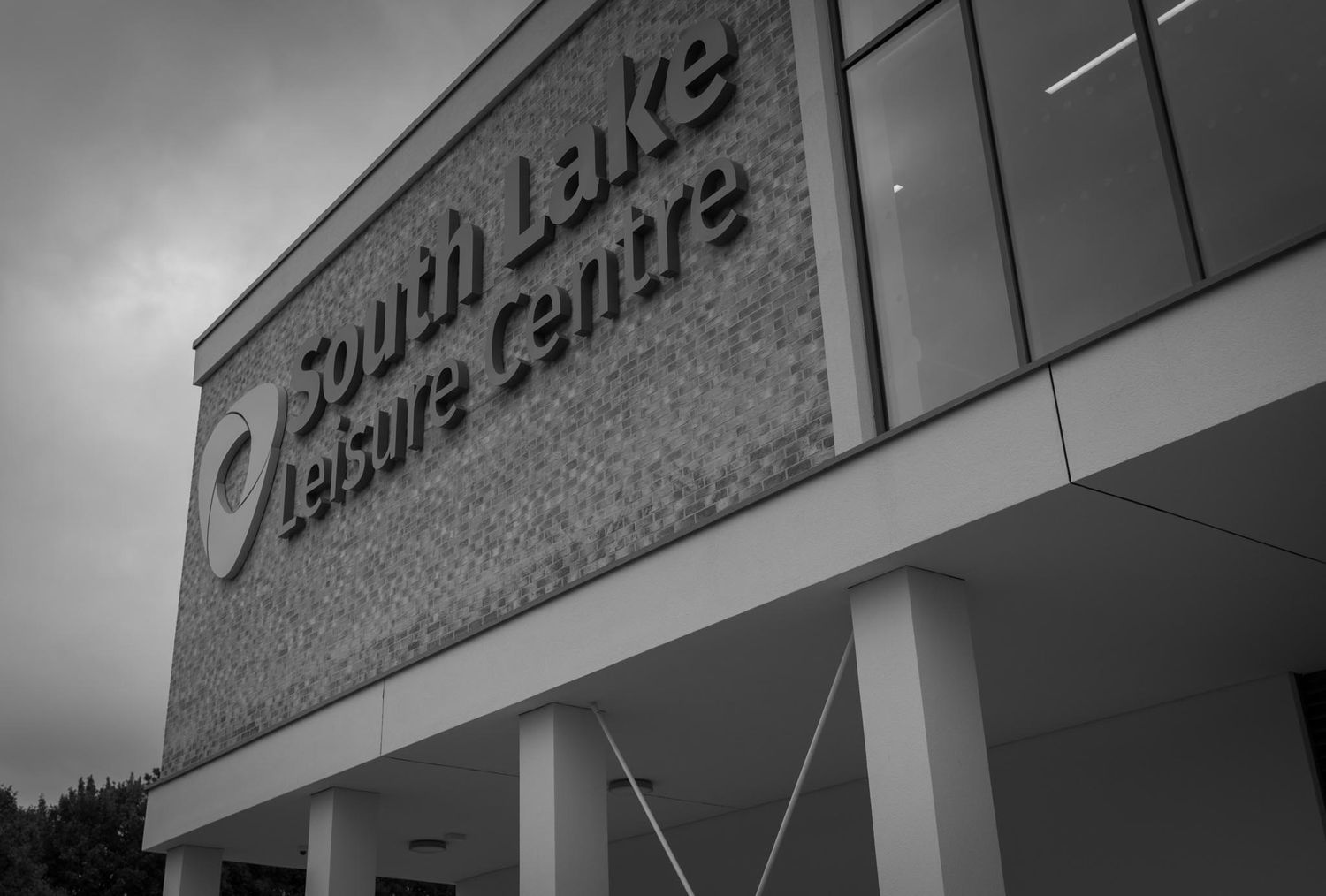 Mono image of the outside of the building, close up with signage on the side of the building.