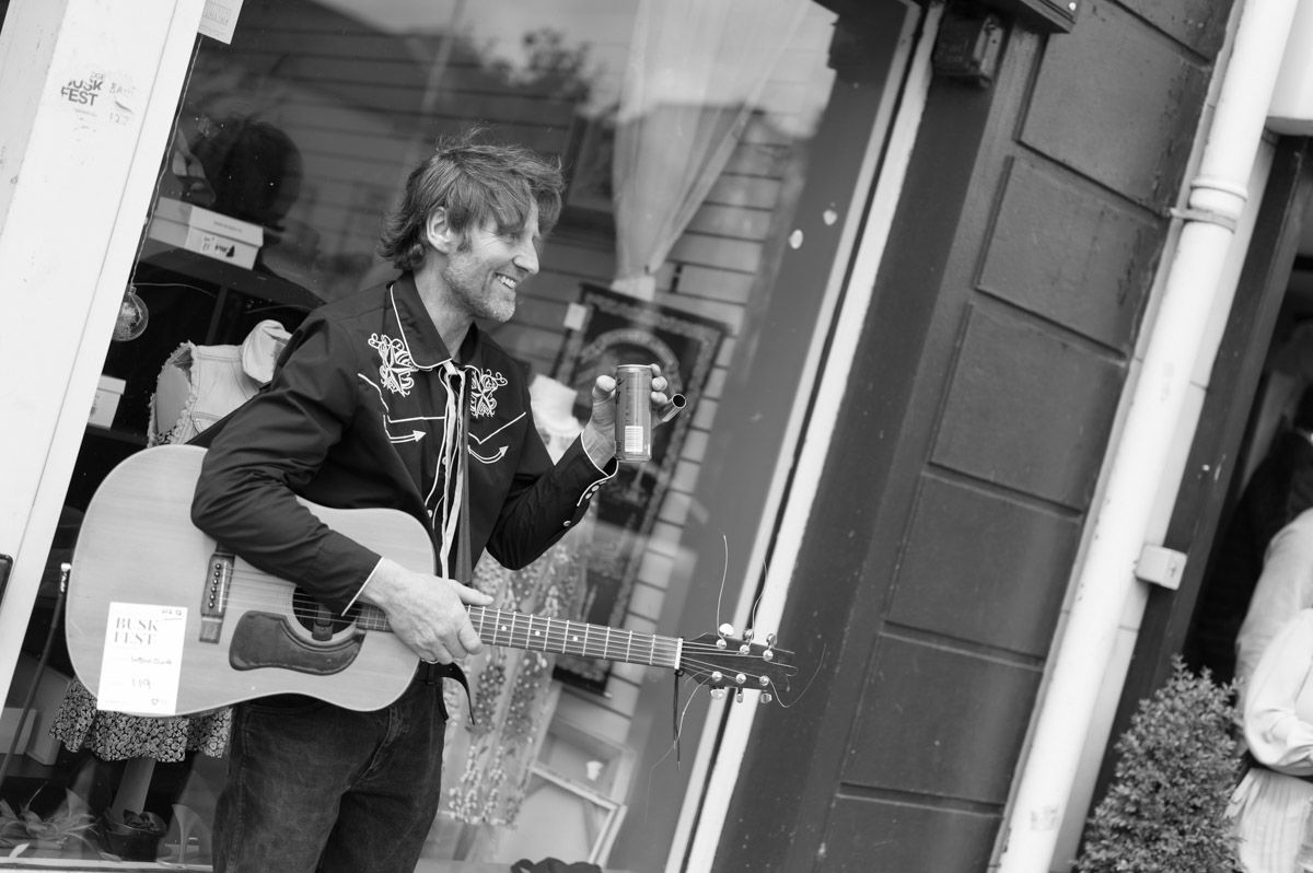 Guitarists smiling with their guitar and a can of drink.