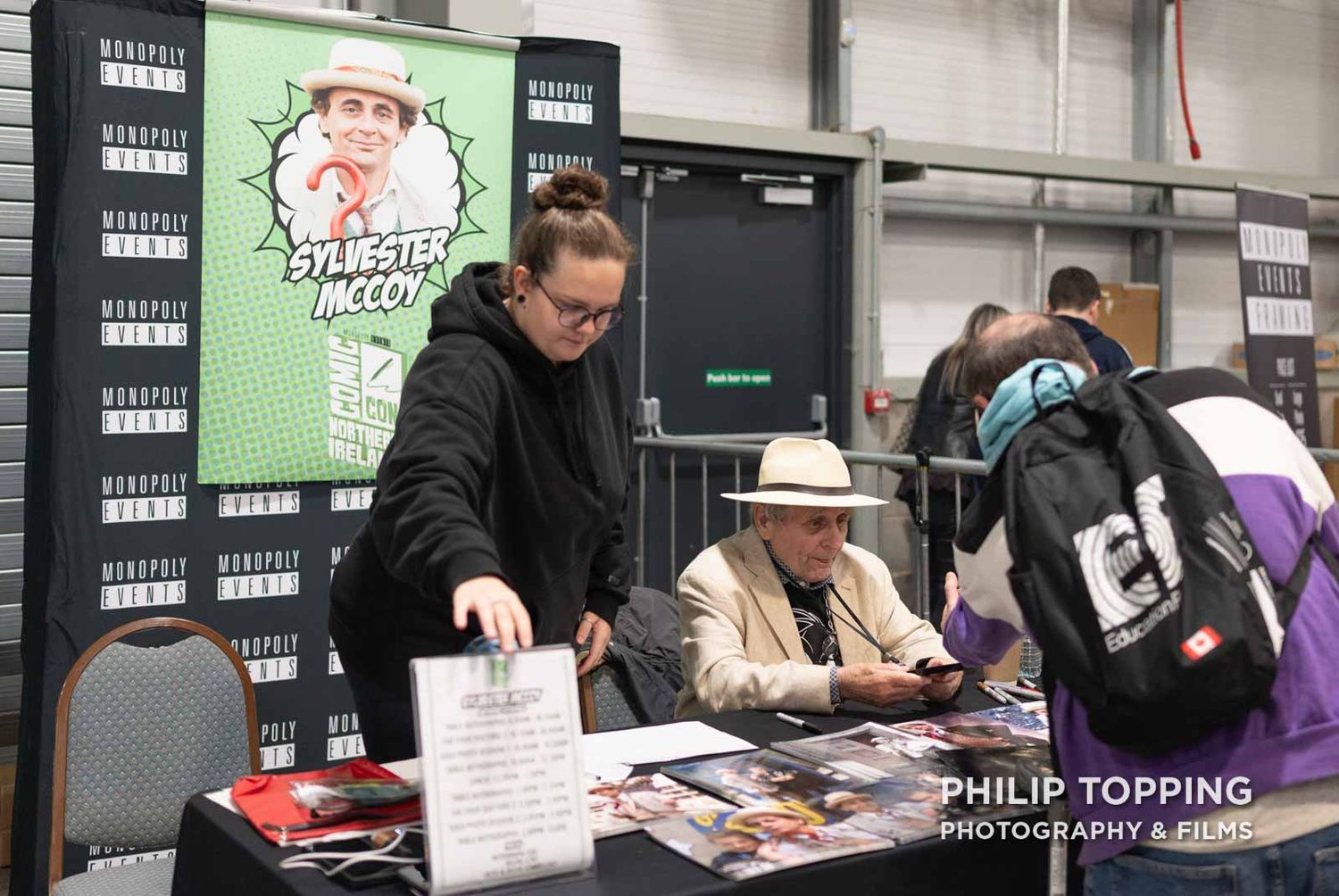 Wider photo of McCoy's table with an assistant standing beside him.