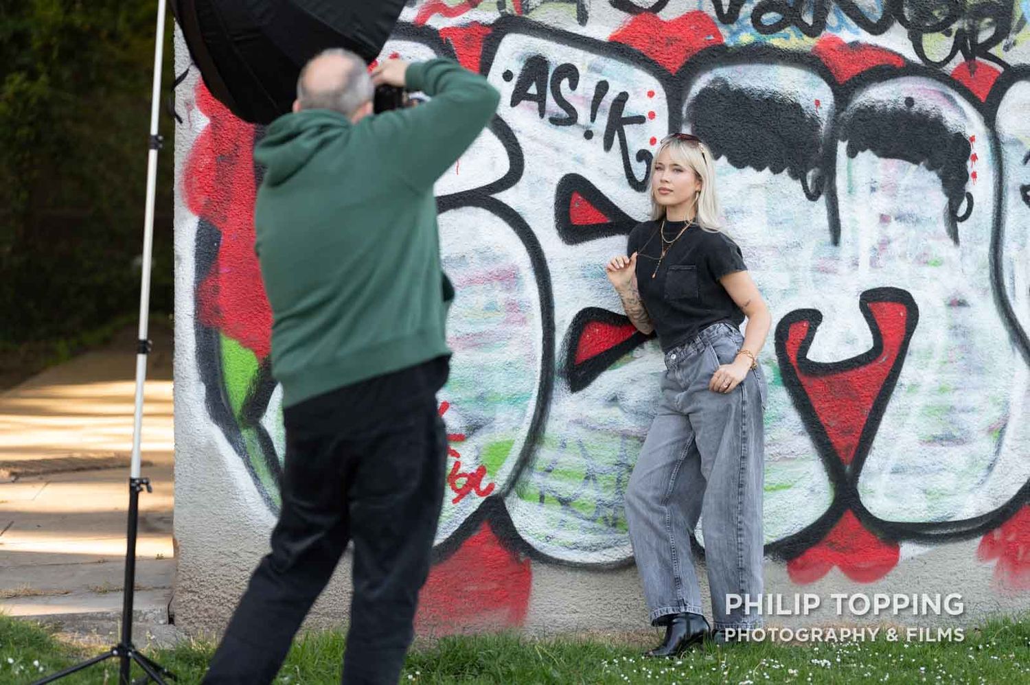 A photographer is taking an image of a female model in front of the graffiti wall.