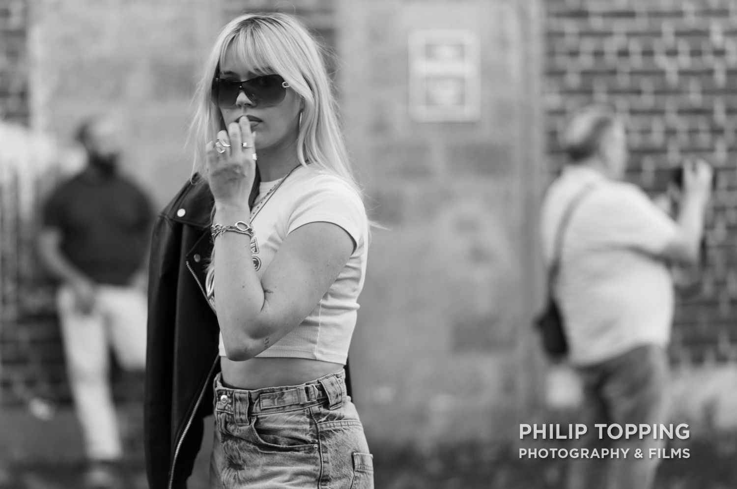 A model takes a break in the foreground as a photographer is taking pictures in the background.