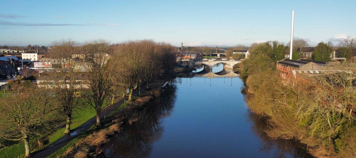 River in foreground with the Bann Bridge in the distance, photographed from above.
