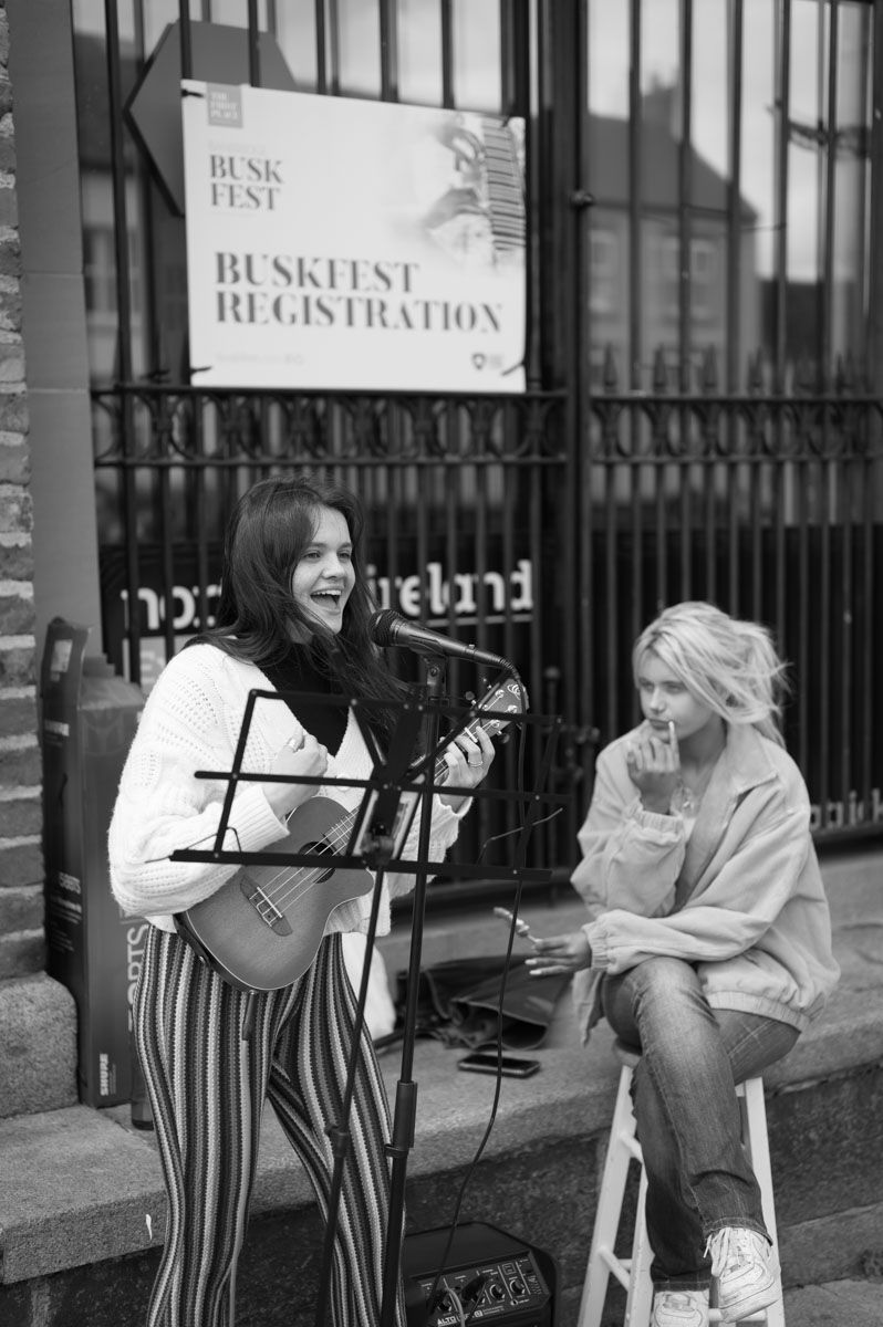 A girl singing with a female sitting beside her, watching and listening.
