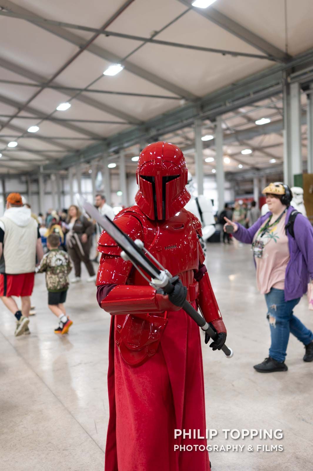 Red cosplayer with a spear posing for a photo.