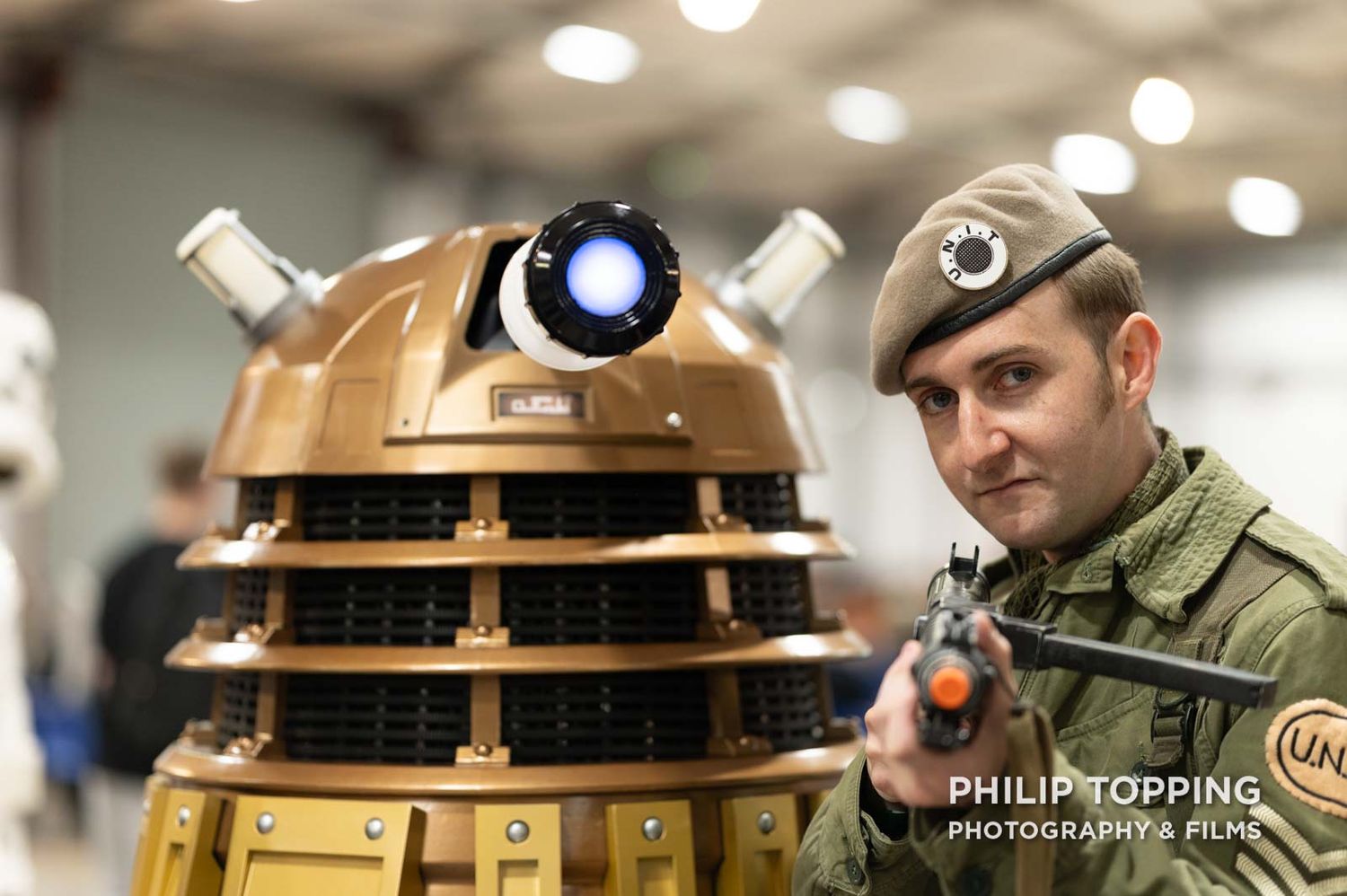 Dalek beside an army cosplyer, pointing his gun at the camera.