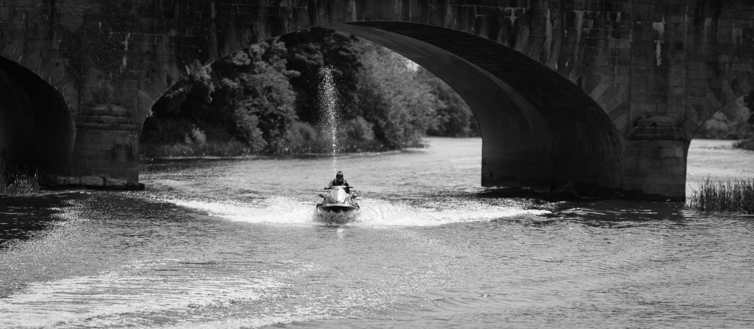 Jet skier skiing under the Northway Railway Bridge.