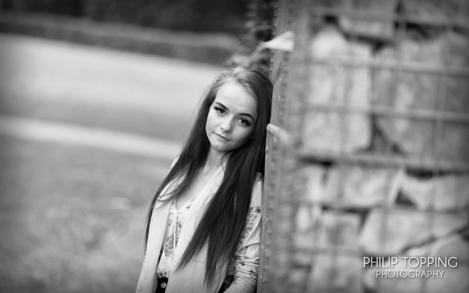 Female leaning against a stone wall, looking at the camera.