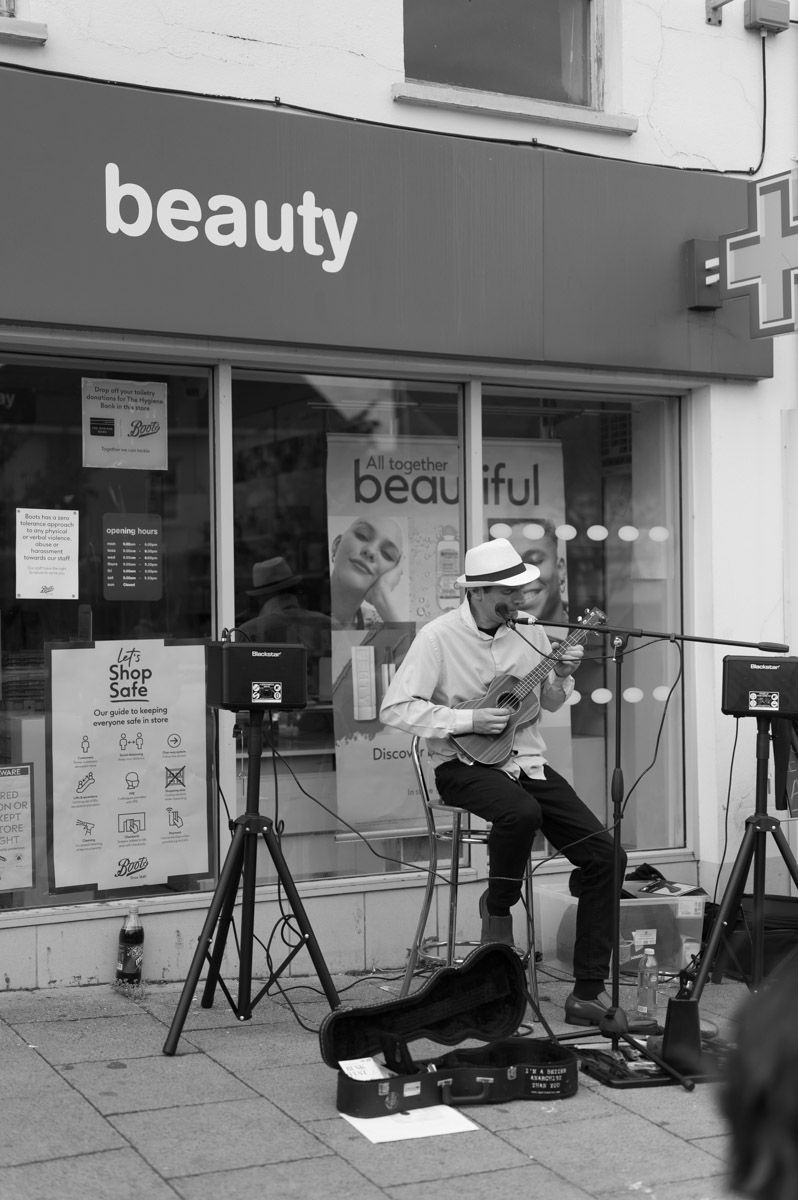 Playing a small guitar sitting down.