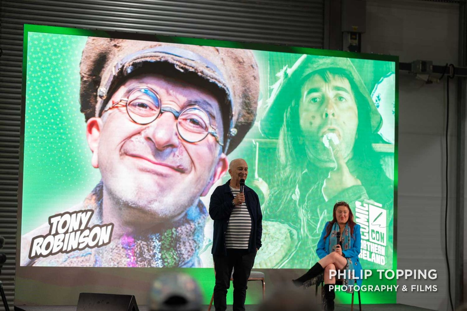 Tony Robinson with a screen showing his Blackadder character from the BBC comedy show.