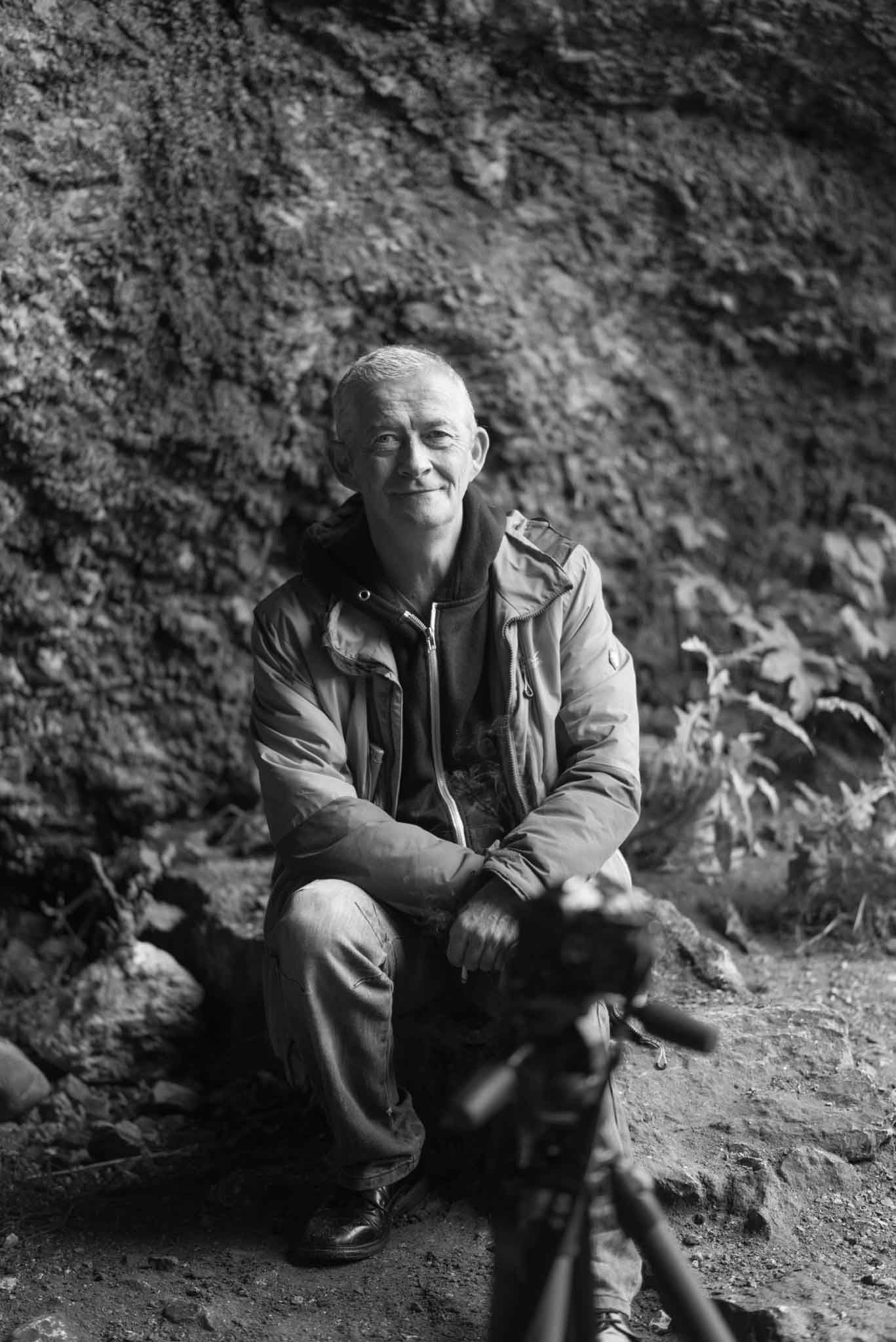 A fellow photo club member is kneeling beside his camera in a cave, looking at Philips' camera.