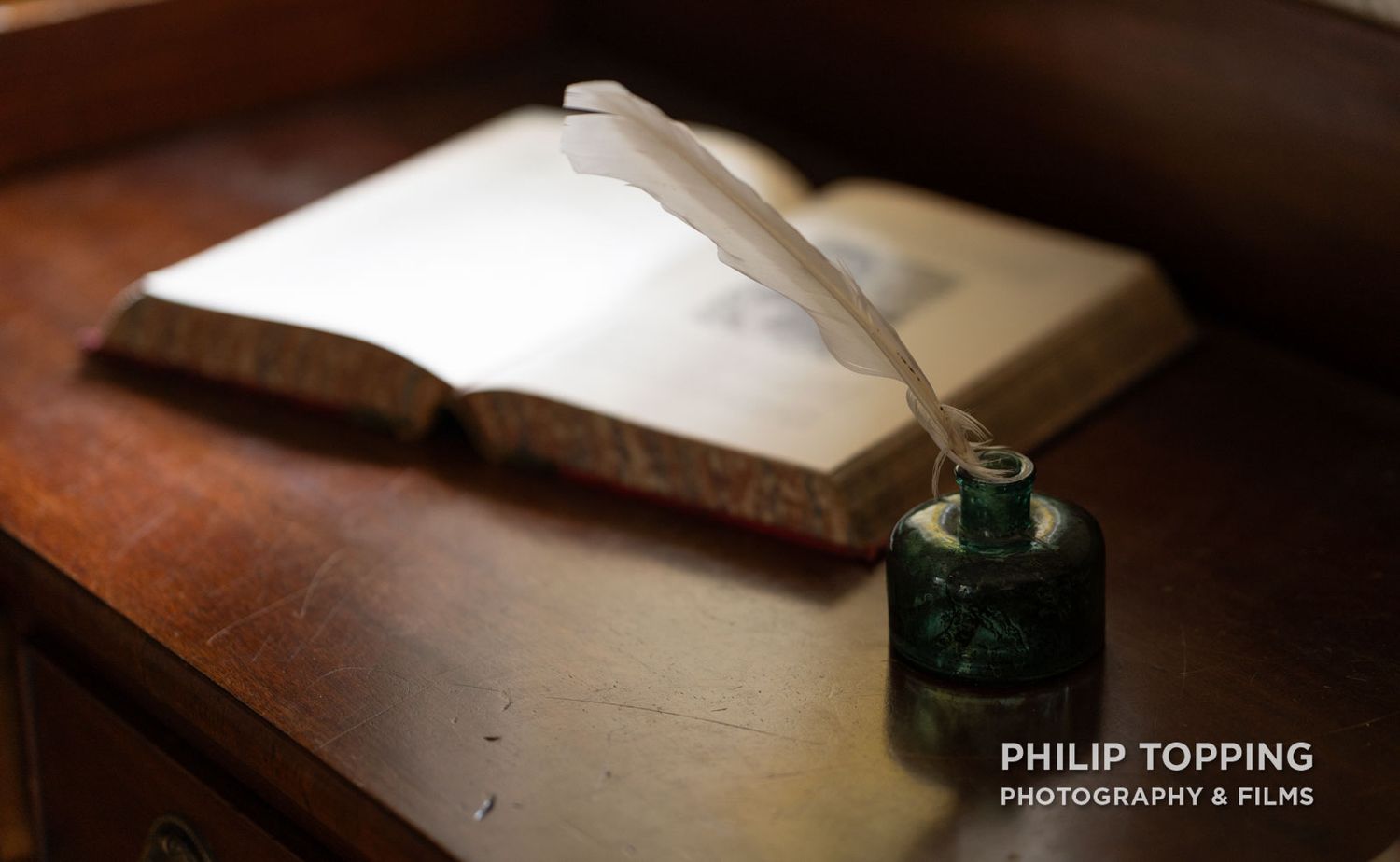 Open the book beside a feather pen in a bottle.