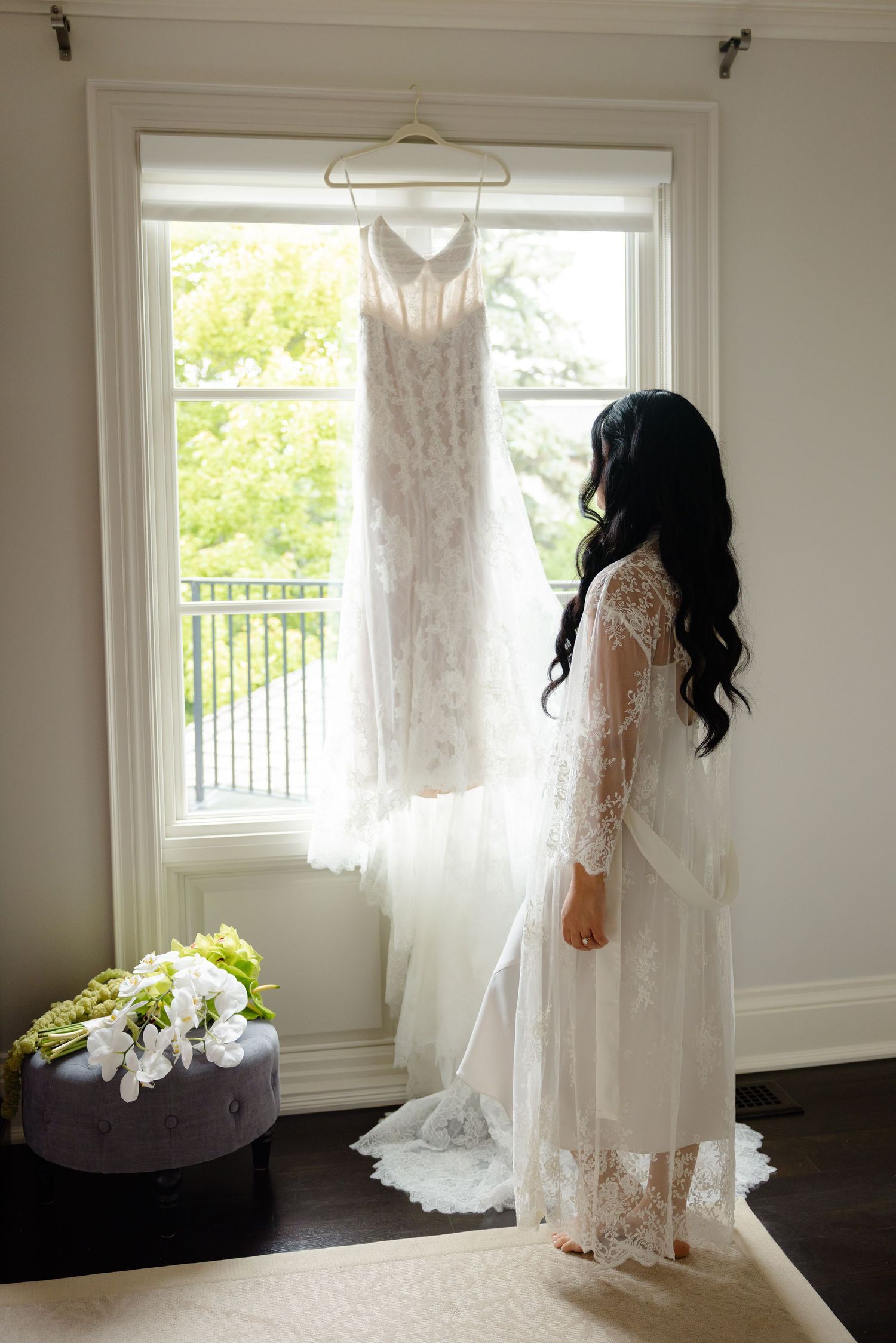 A series of five photos showing a delicate lace wedding dress hanging against white walls in natural window light.
