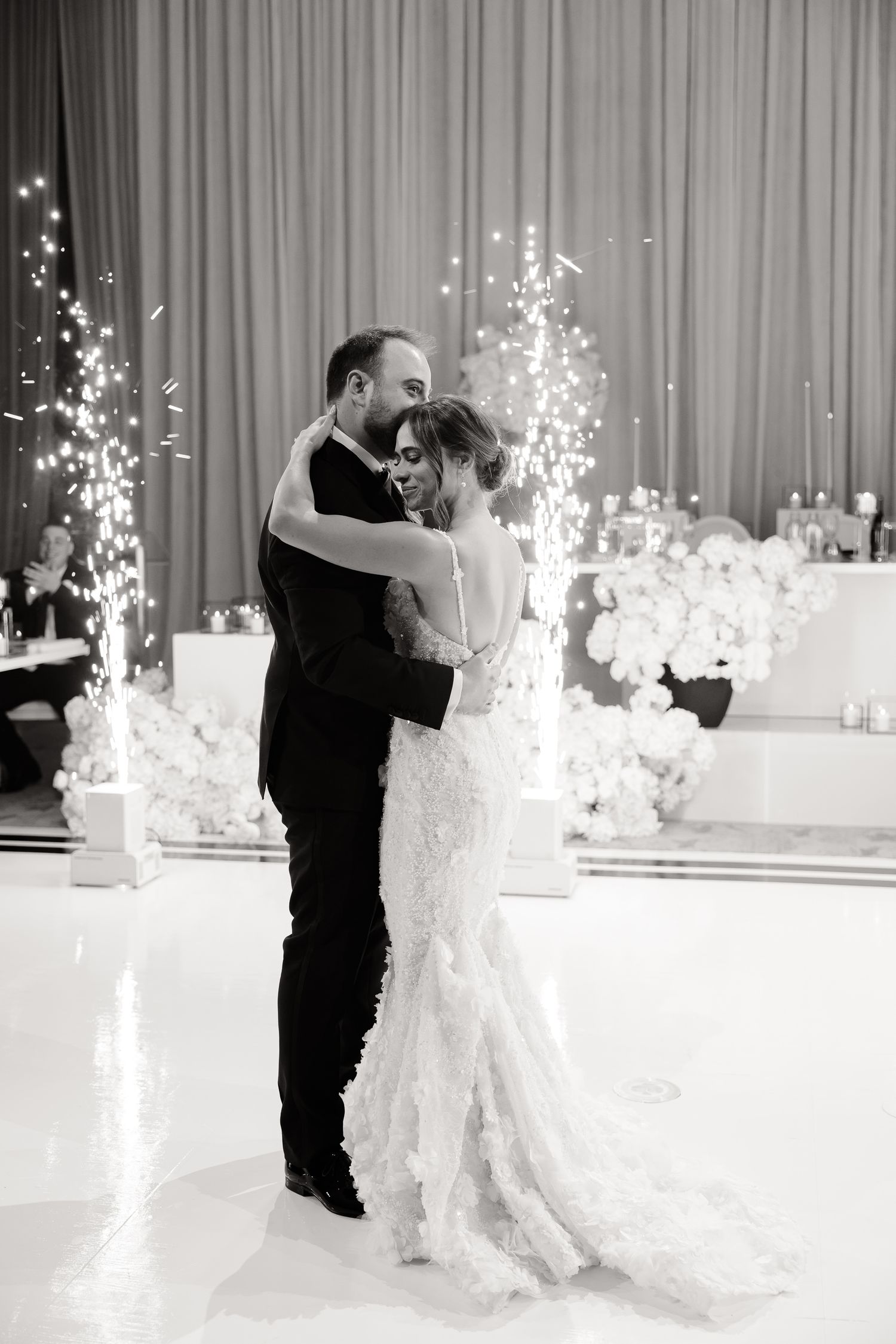 A couple shares their first dance as newlyweds with sparklers creating magical light effects in an elegant reception hall.