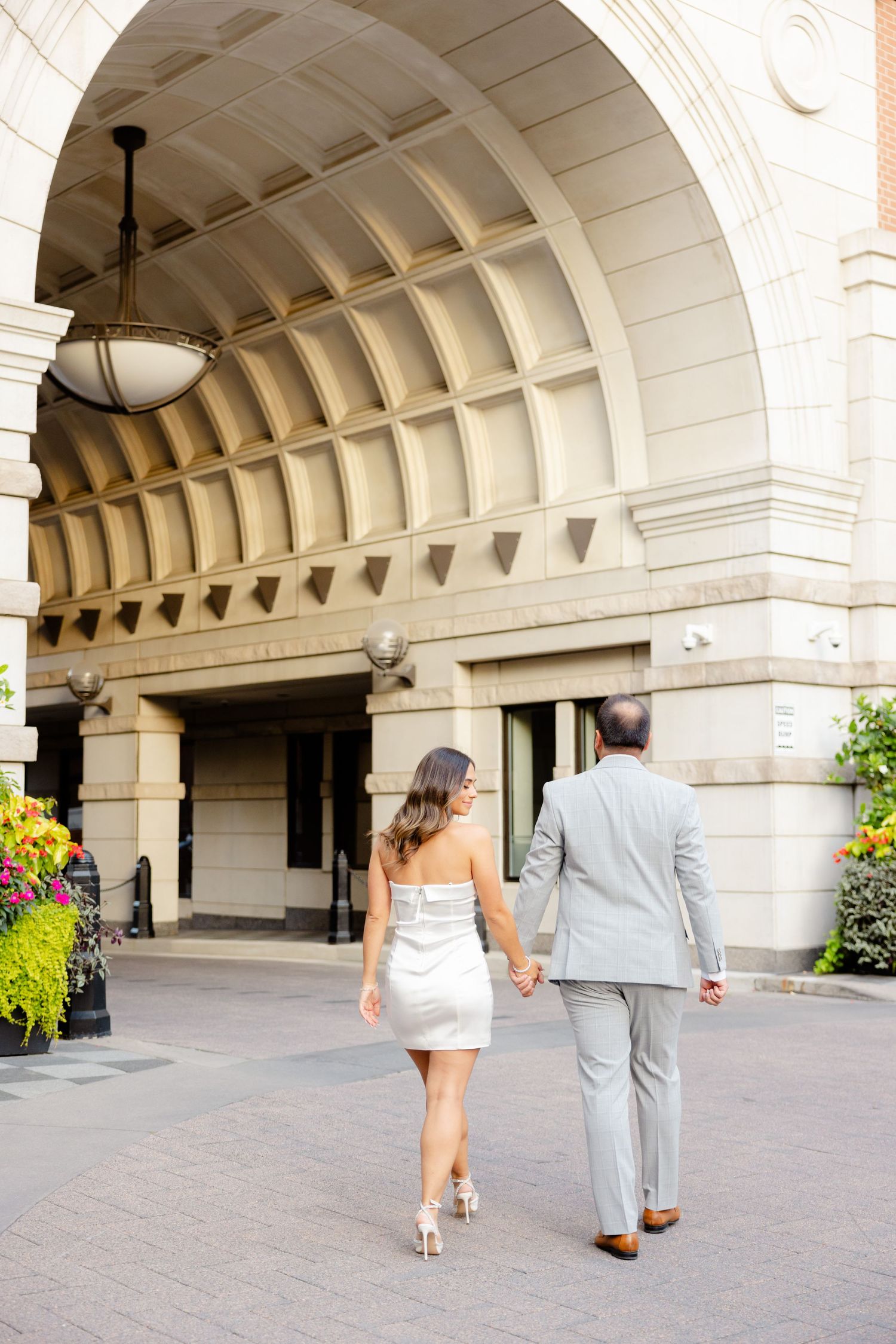 Couple walking away beneath vintage arched entryway with decorative ceiling.