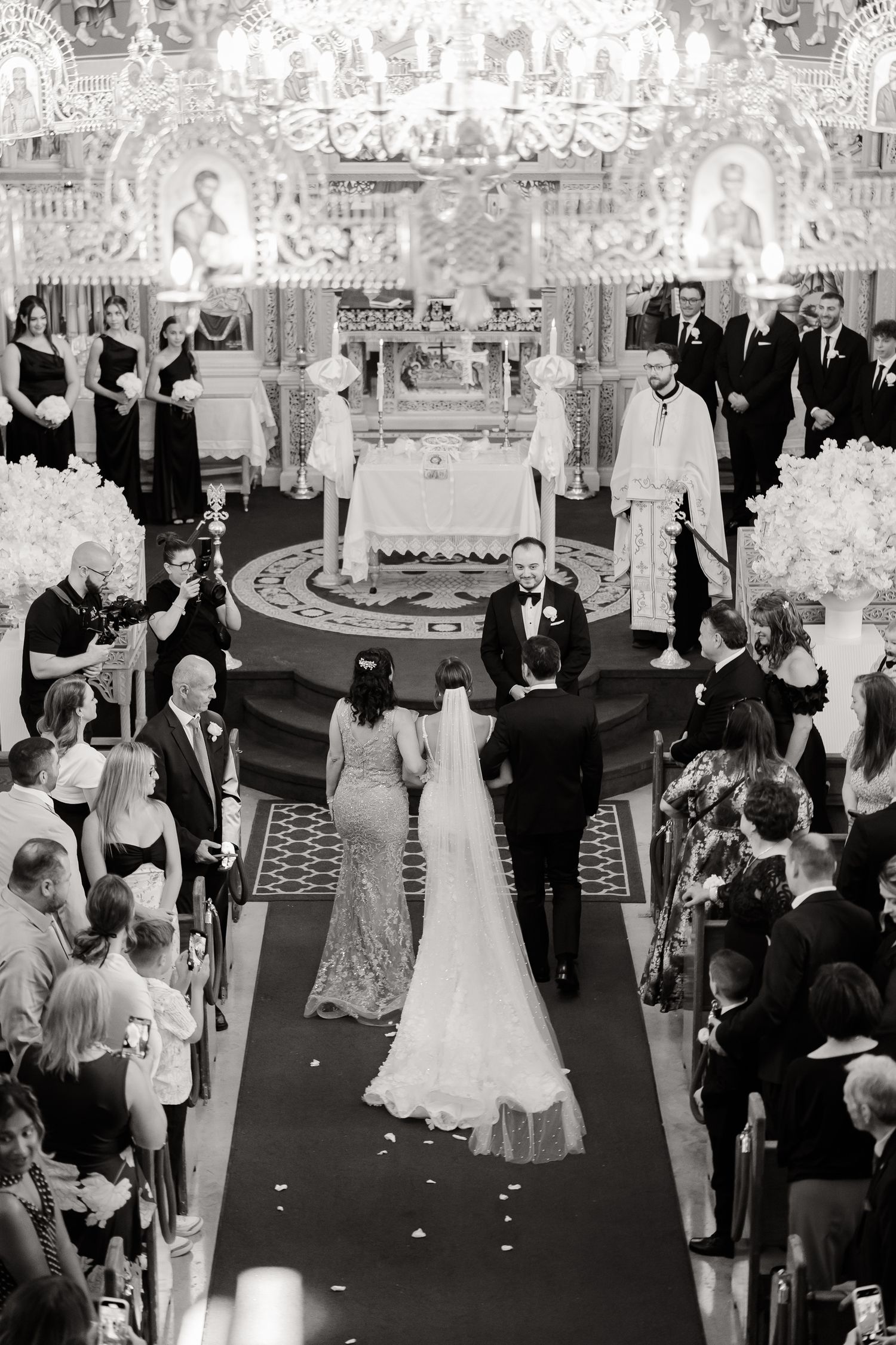 A formal event shows guests standing in a line during a wedding ceremony procession in an ornate hall.