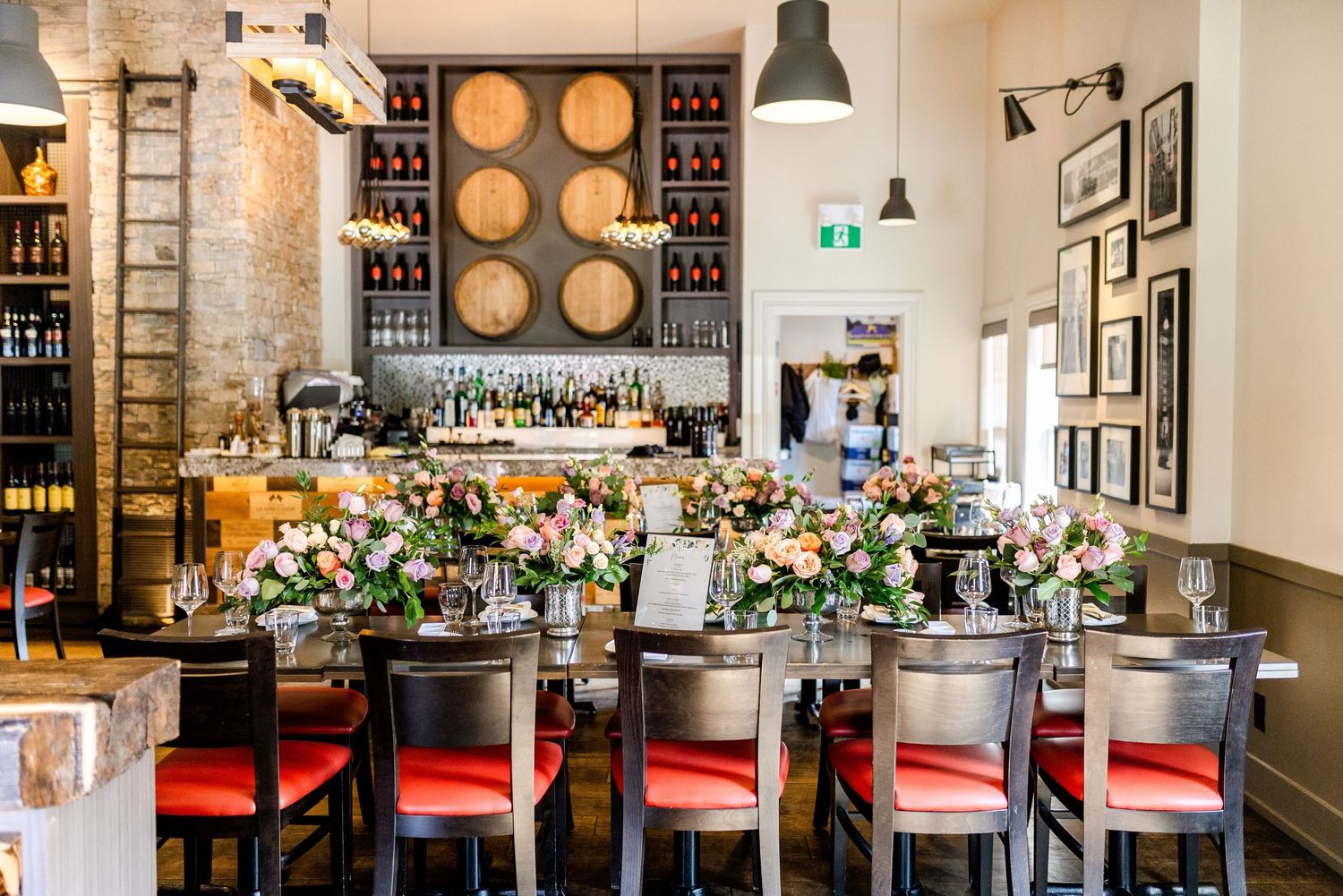 Elegant restaurant bar interior with floral arrangements and red bar stools along the counter.