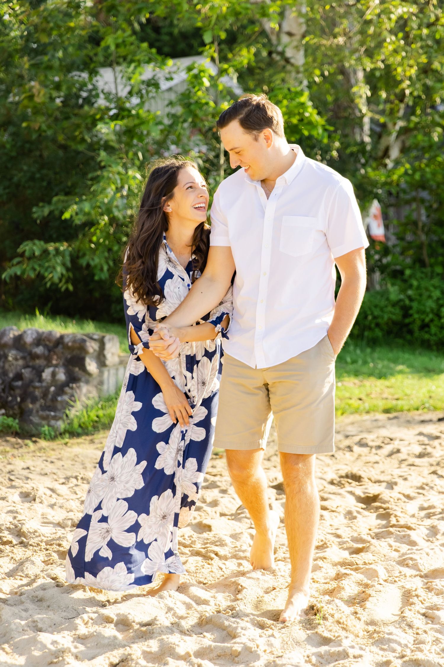 Couple sharing a playful moment on a sunny beach while wearing coordinated summer outfits.