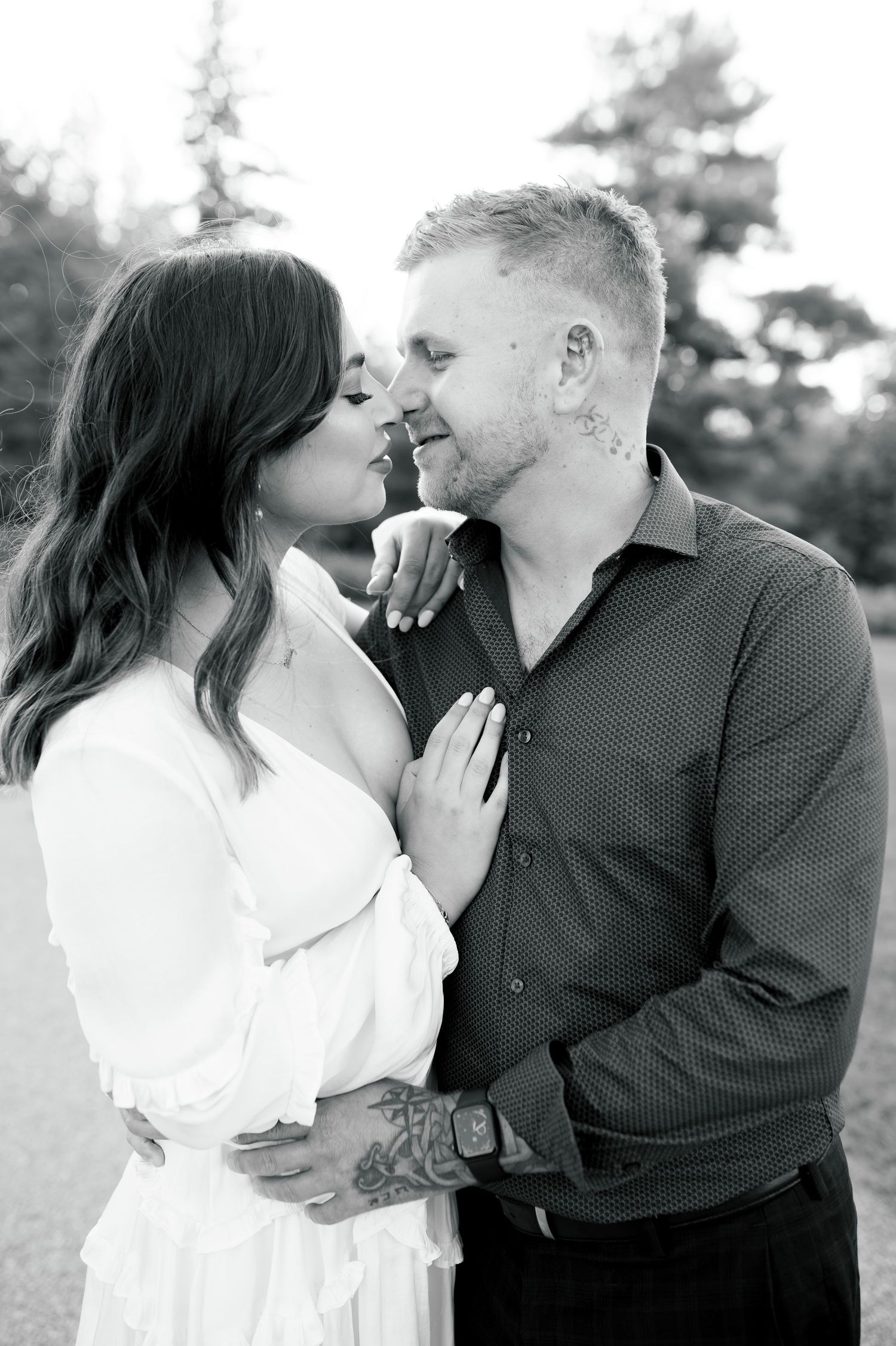 Black and white intimate portrait of couple sharing tender moment outdoors.