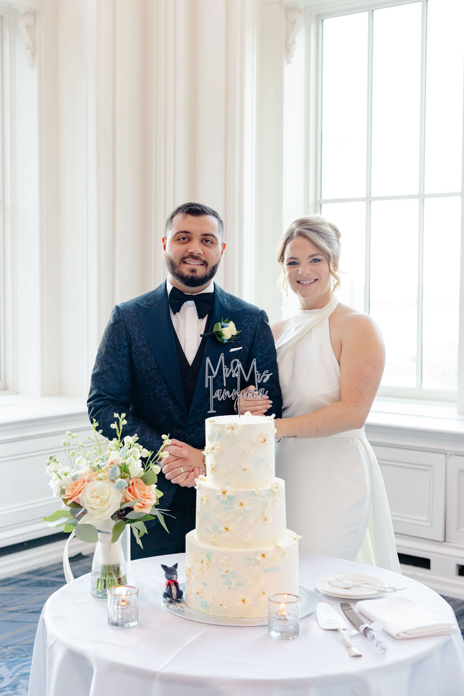 Wedding cake display with a white tiered cake decorated with blue accents on an elegant table setting.