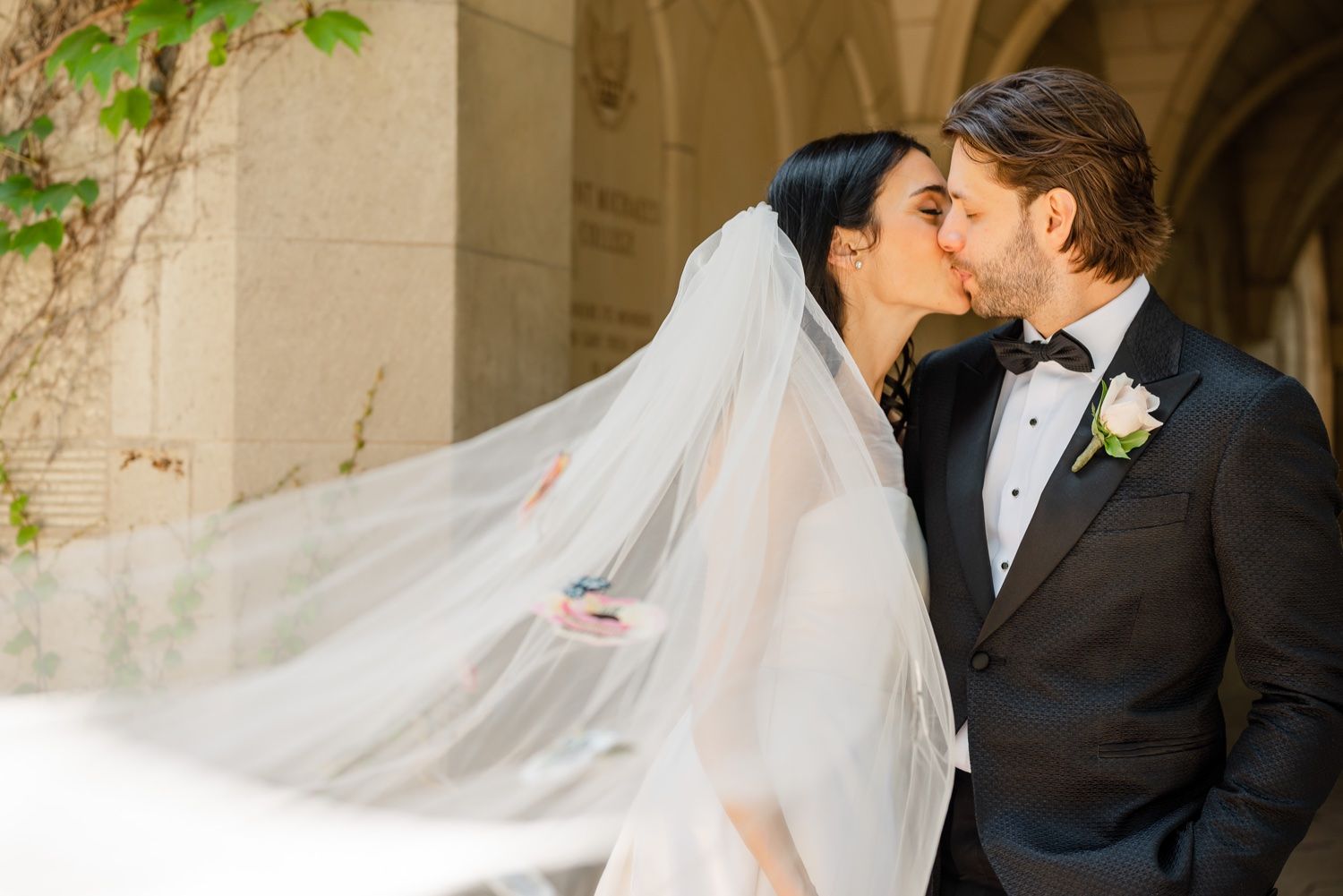 A bride and groom share a tender kiss as her veil flows in the breeze.