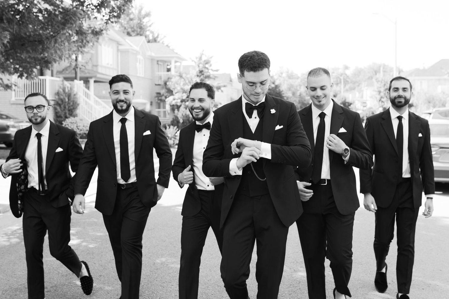 Group walking together outdoors in formal suits and ties in black and white photography.