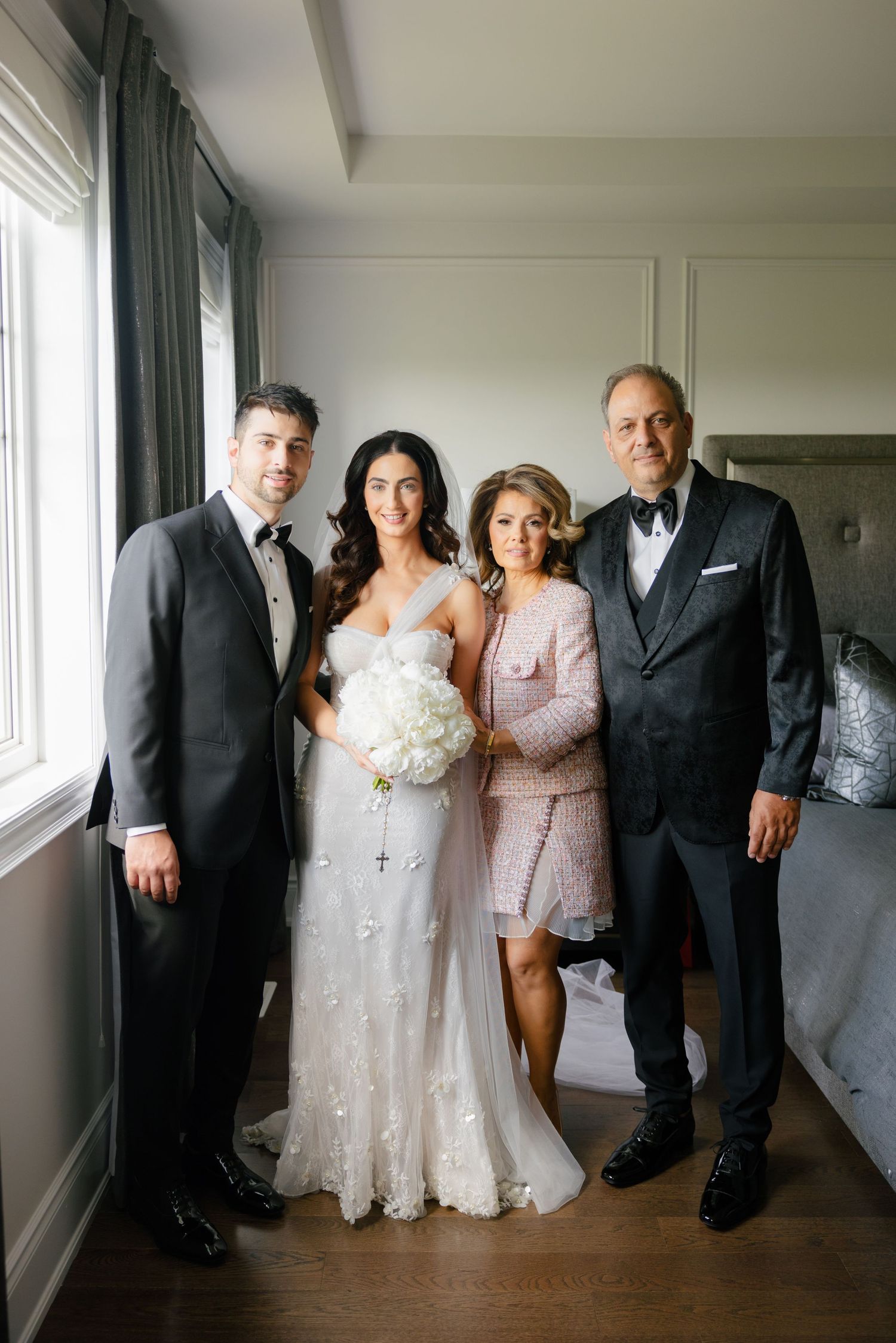 A wedding party portrait in a modern room with floor-to-ceiling windows and green curtains.