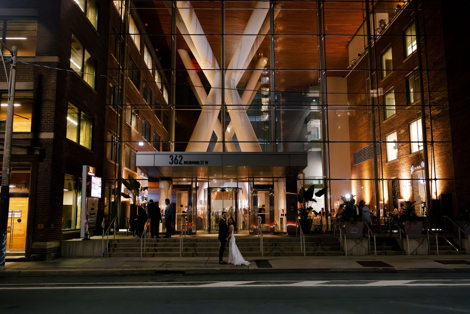 Dramatic nighttime architectural shot of modern building entrance with illuminated X-shaped beams.