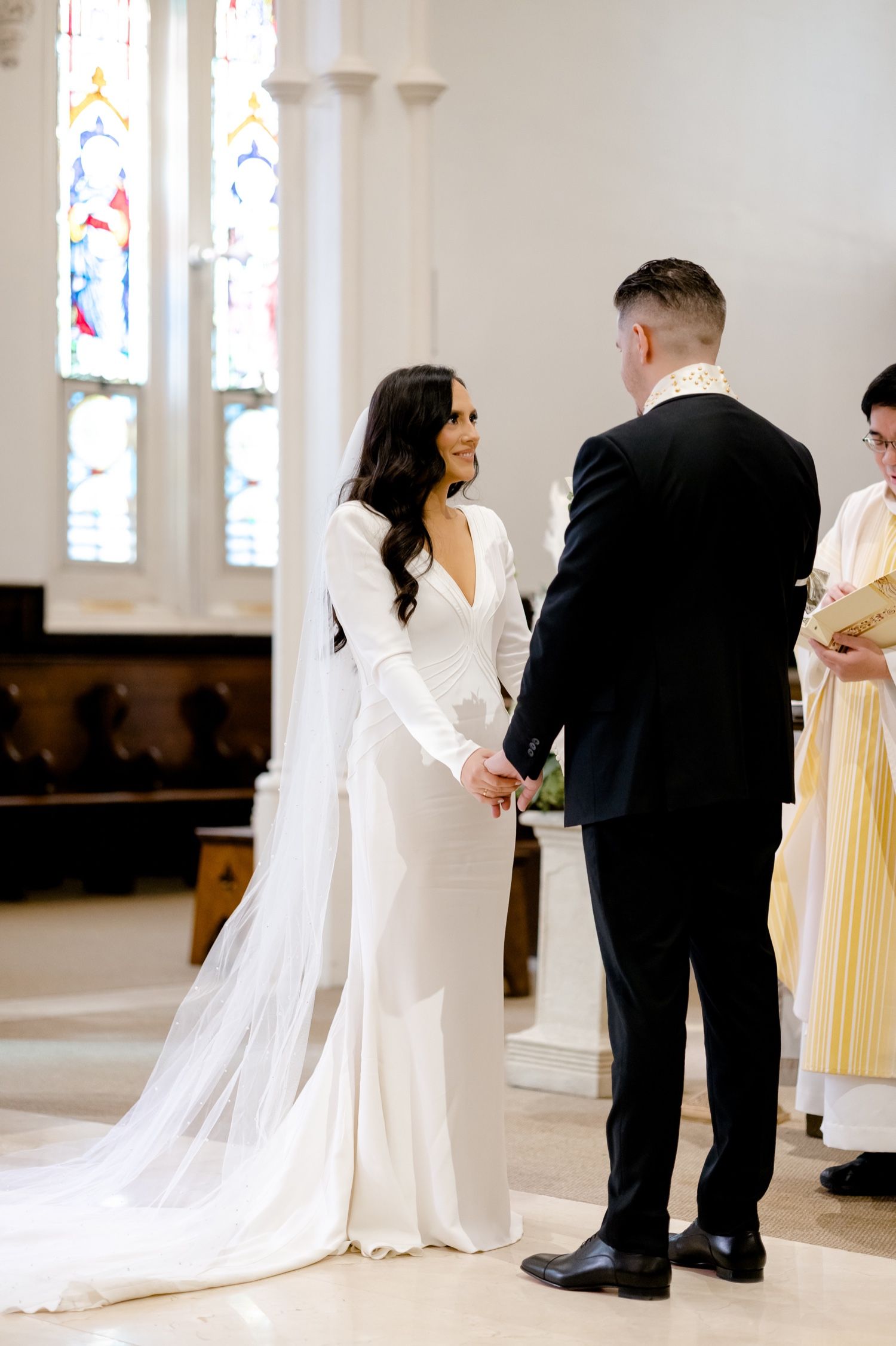 Elegant church wedding ceremony with couple exchanging vows beneath stained glass windows.