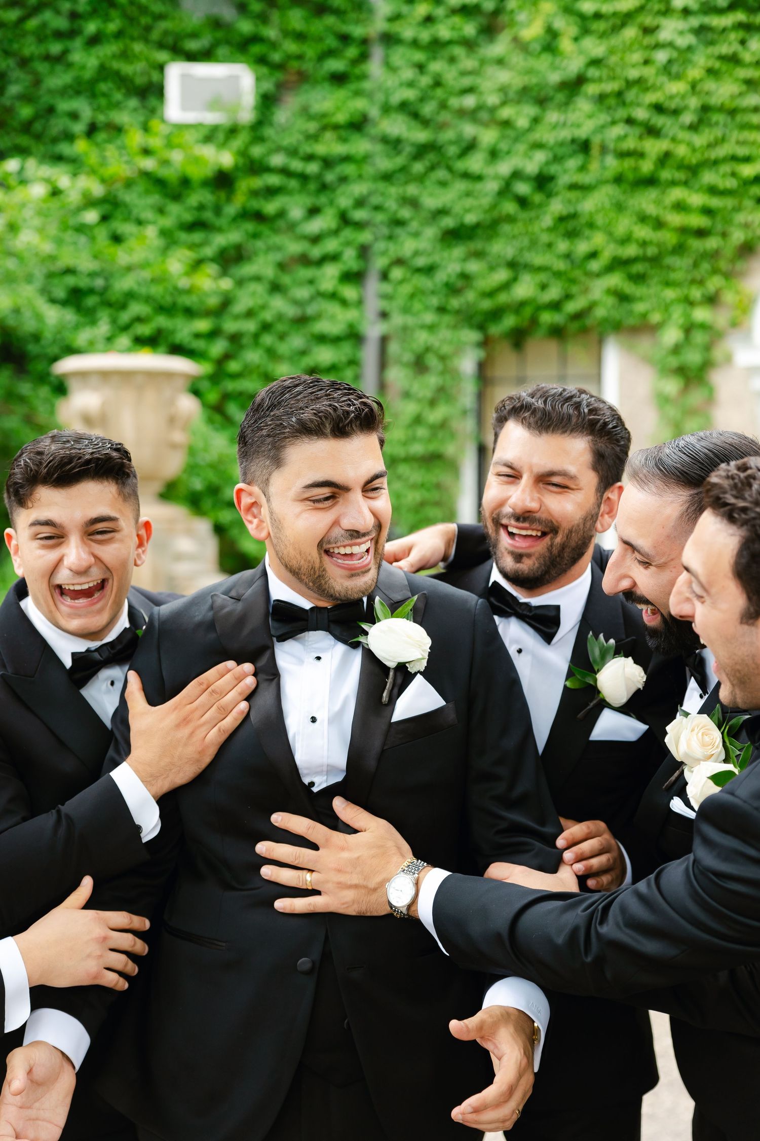 Candid shot of groomsmen laughing together while wearing classic black tuxedos.