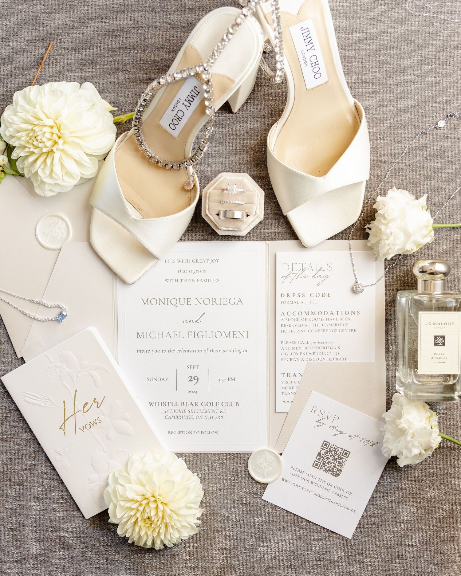 Elegant wedding details including Jimmy Choo shoes, white invitations and cream flowers on a gray surface.
