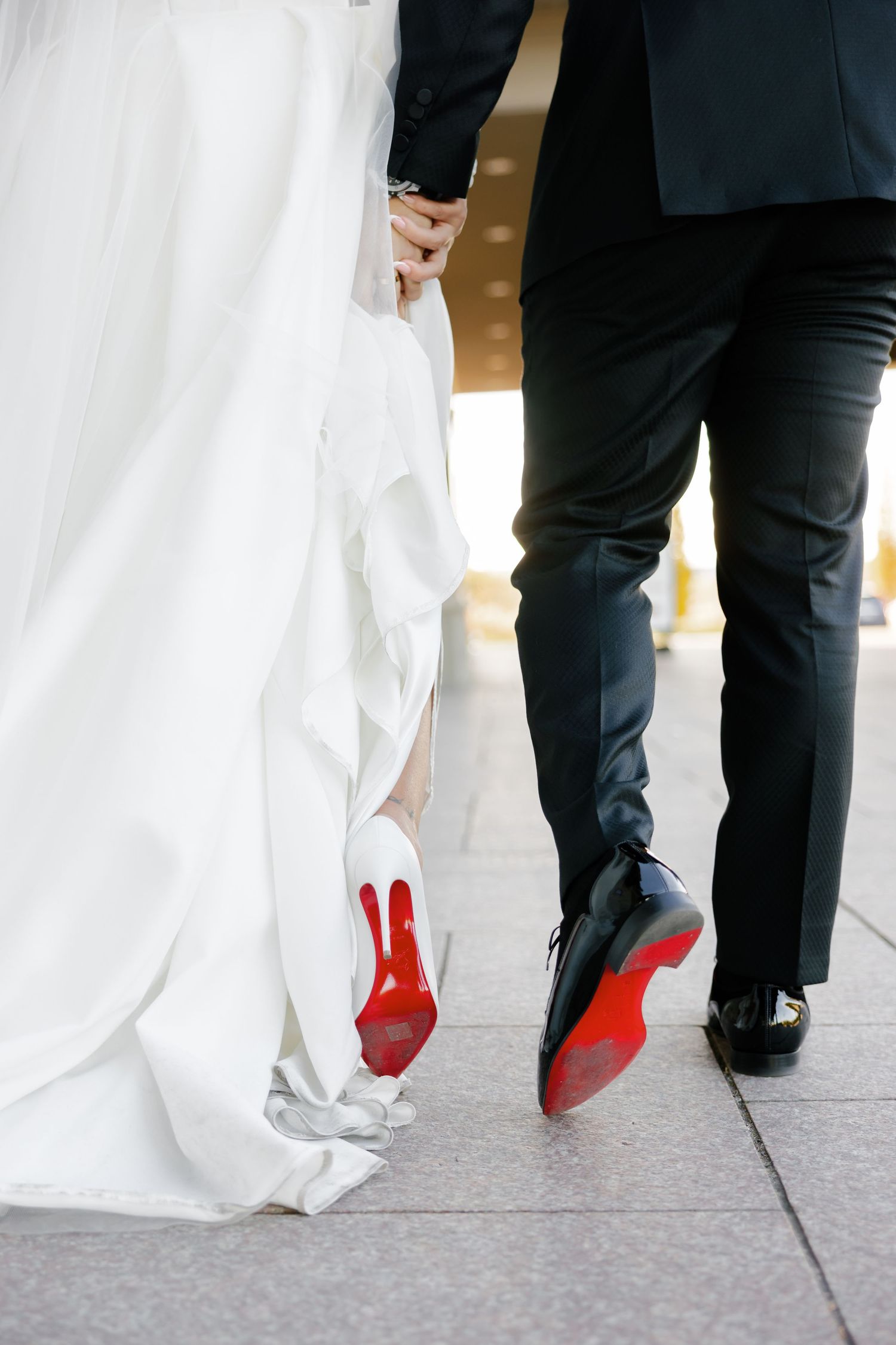 Detail shot of wedding couple's shoes showing red soles while walking.