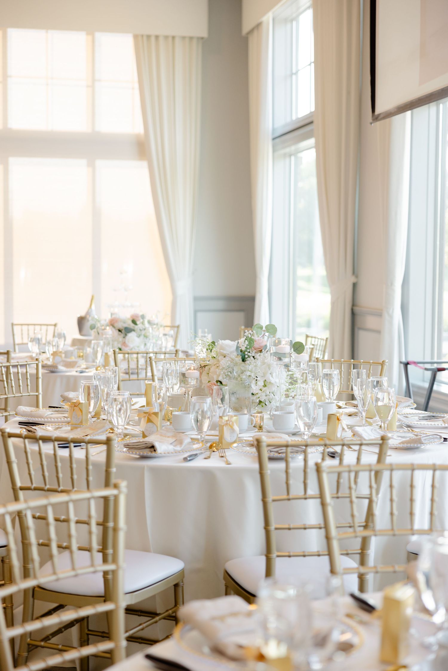 Wedding table decor with gold and white place settings and soft floral arrangements.