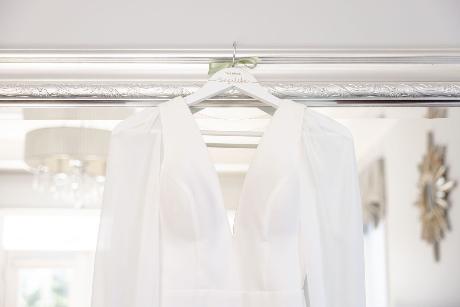 Elegant white wedding dress hanging on display against ornate white molding.