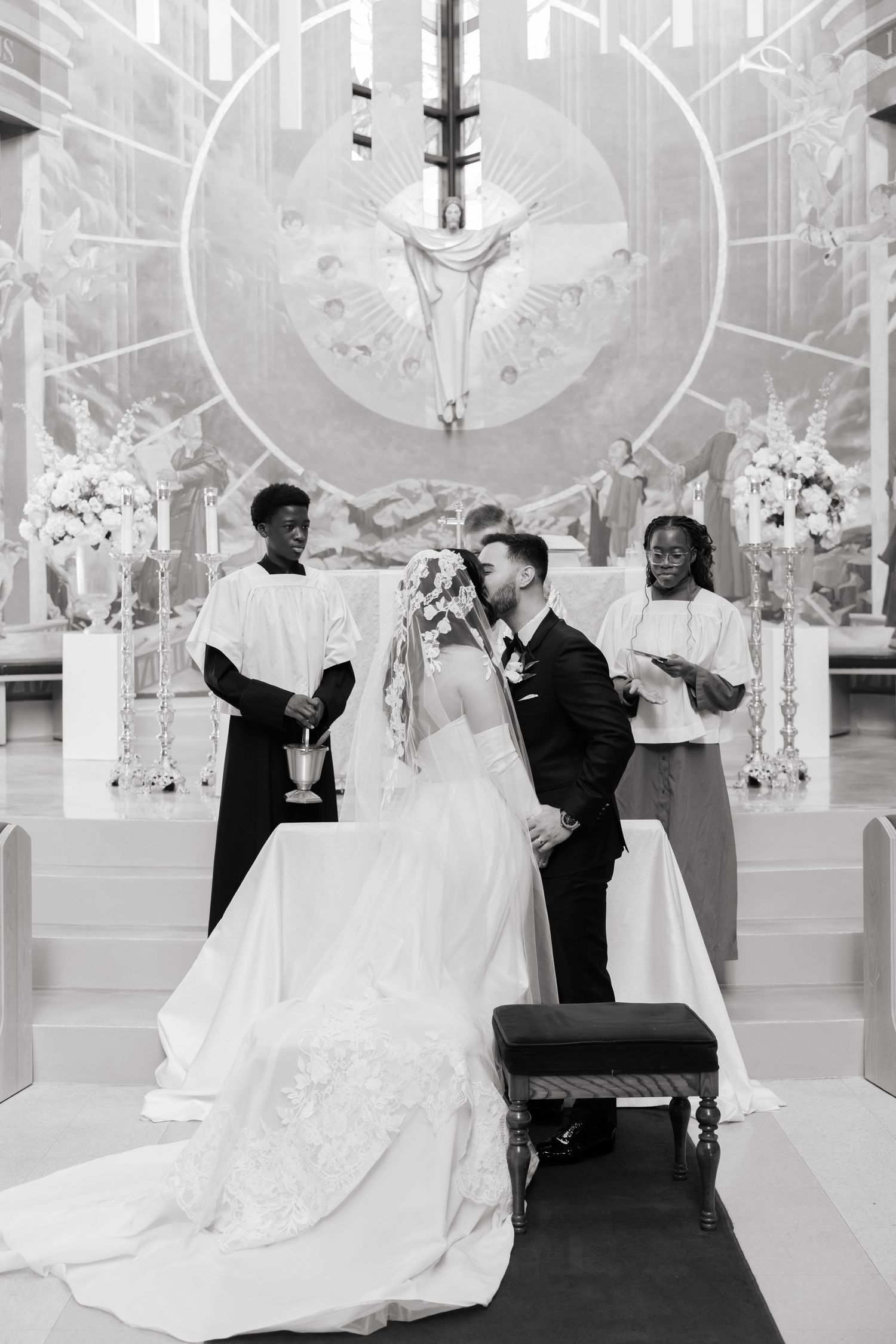 Black and white photo of a wedding ceremony in a beautifully decorated church sanctuary.