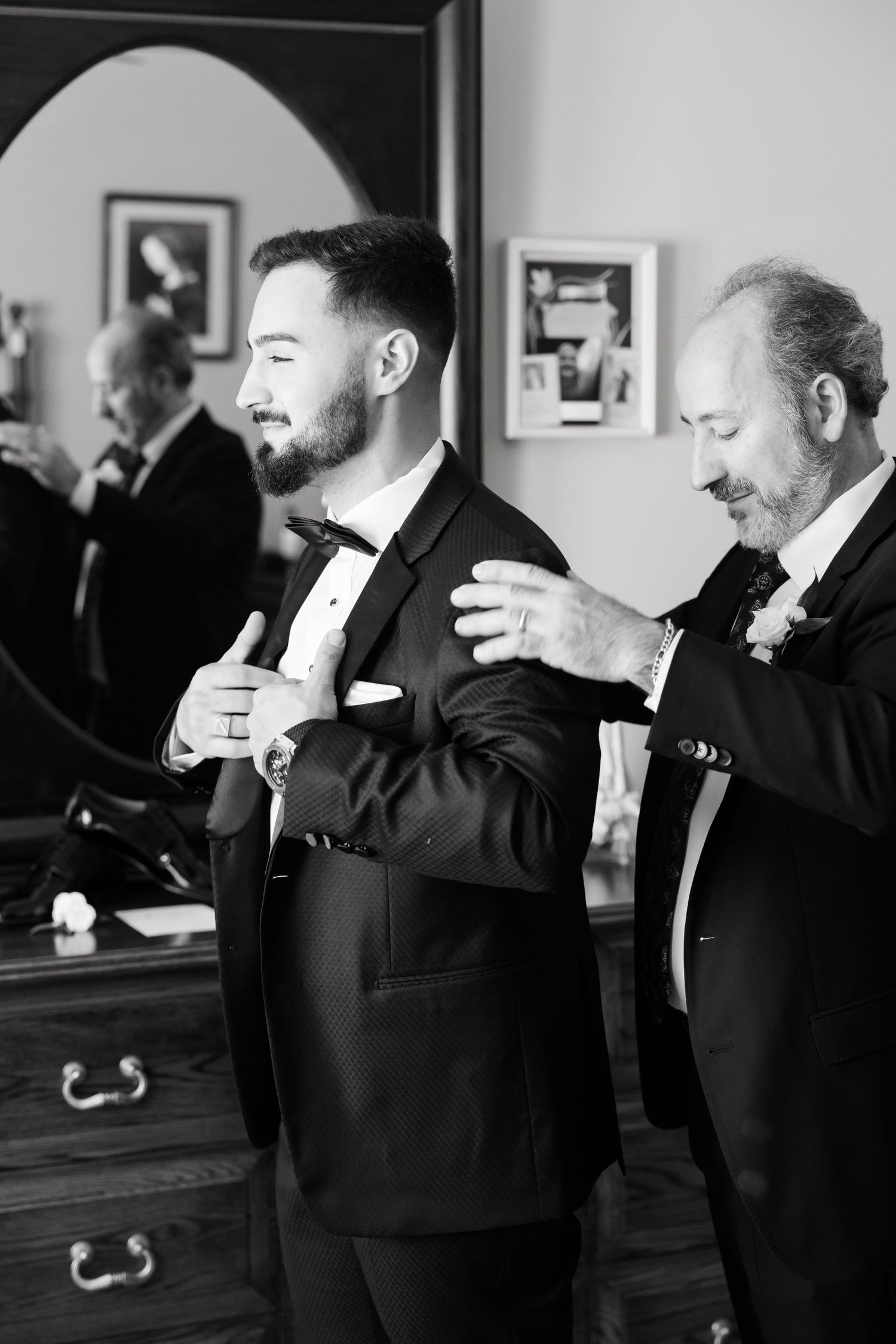 Black and white image of formal dress preparation with vintage furniture in background.