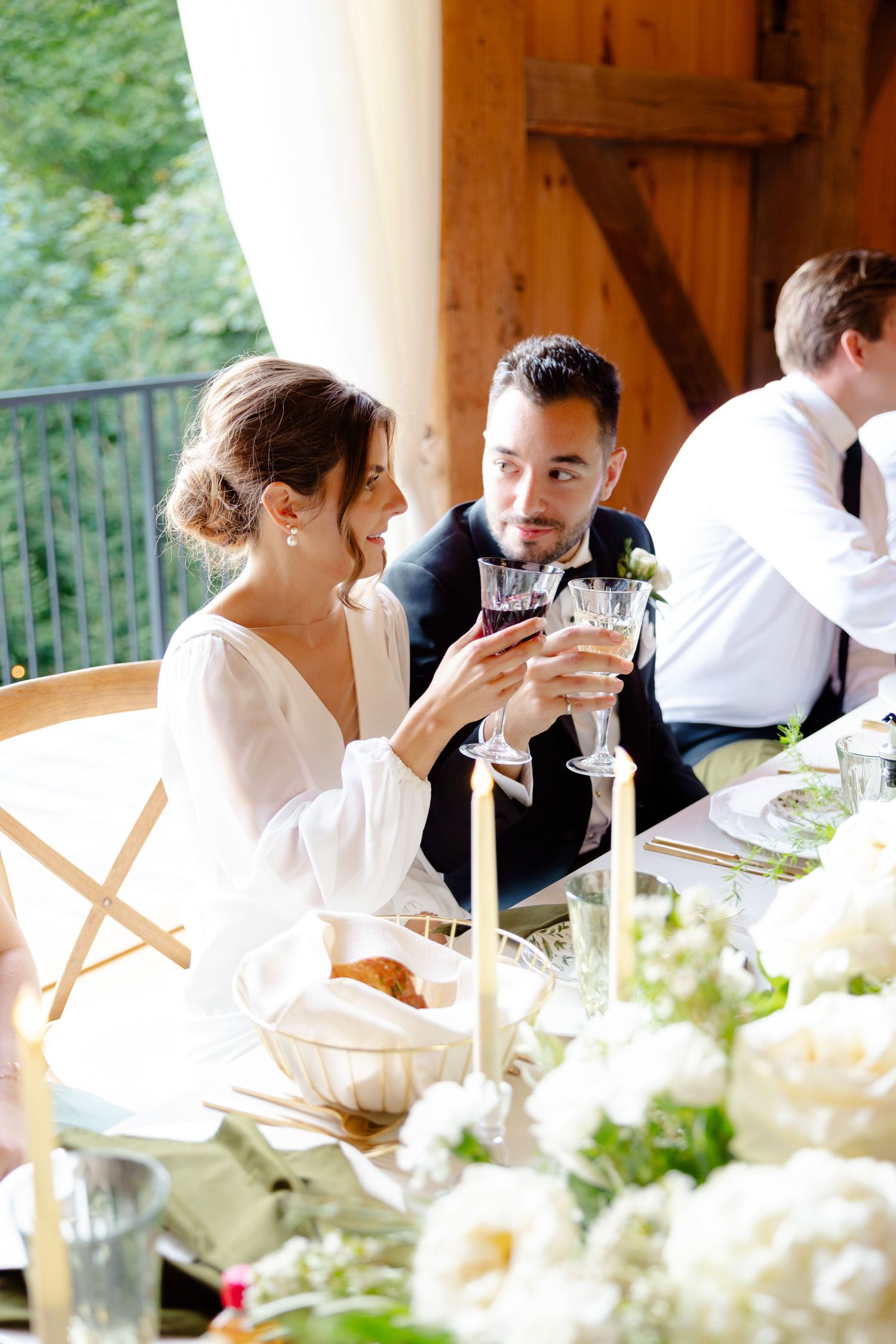 Wedding reception table scene with elegant table settings and white floral centerpieces.