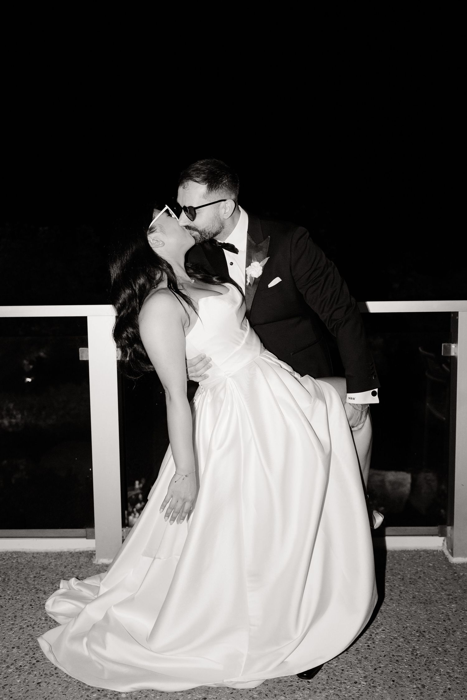 Romantic black and white portrait of couple embracing on outdoor balcony.