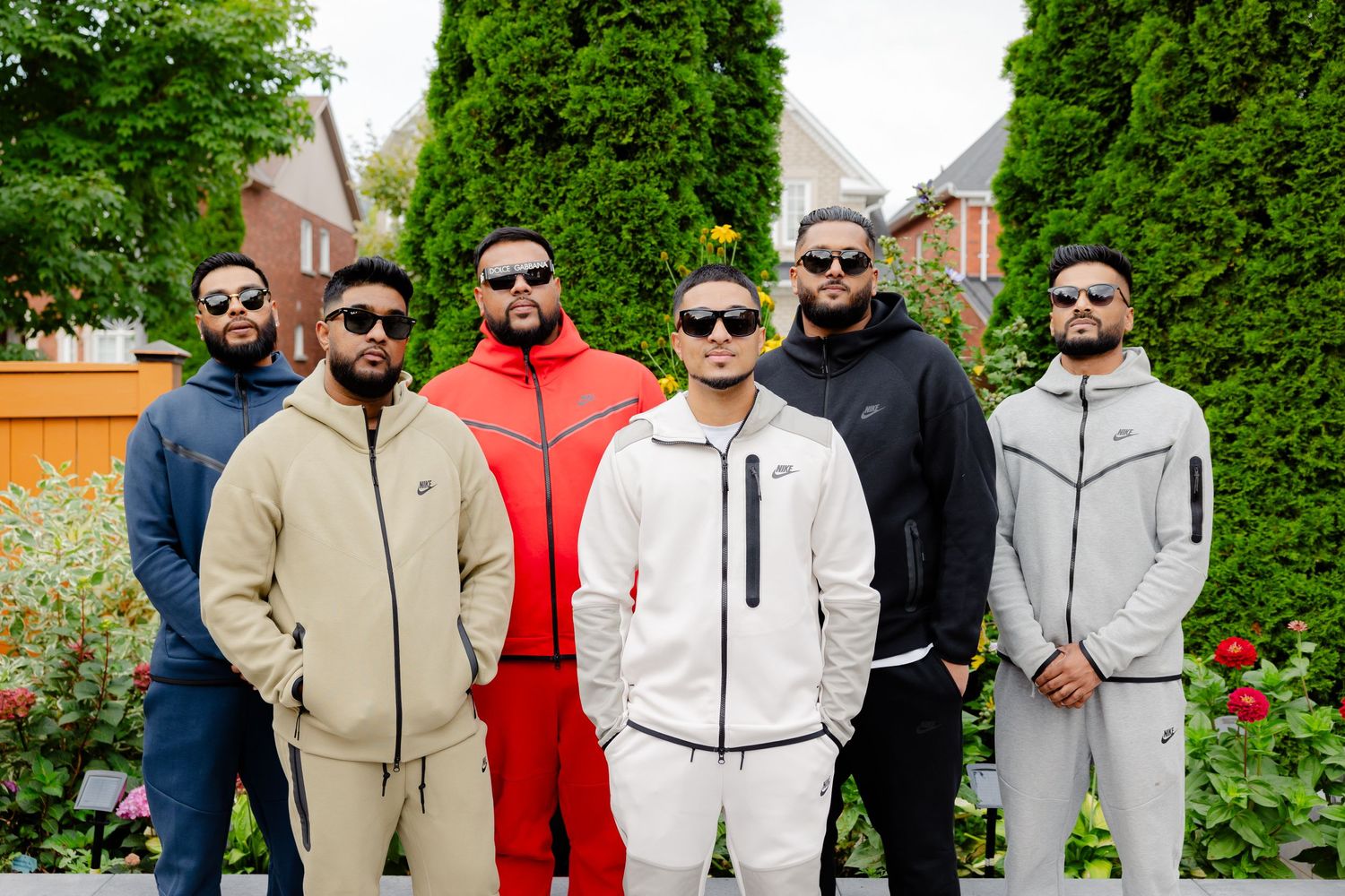 Group shot of friends in coordinated athleisure outfits standing in a landscaped yard.