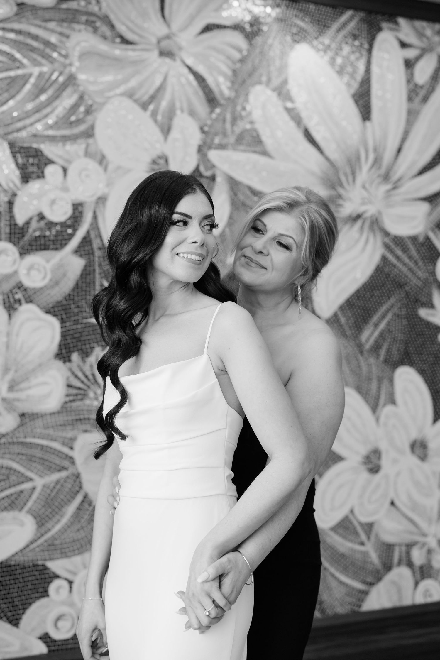 Black and white portrait of two people embracing during wedding preparations.