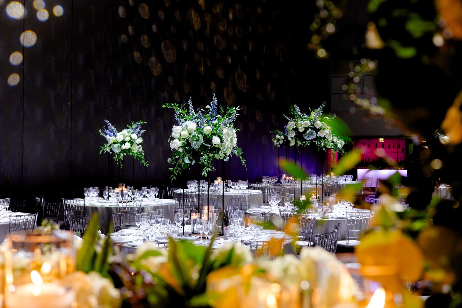 Elegant wedding reception venue with illuminated floral centerpieces and table settings.