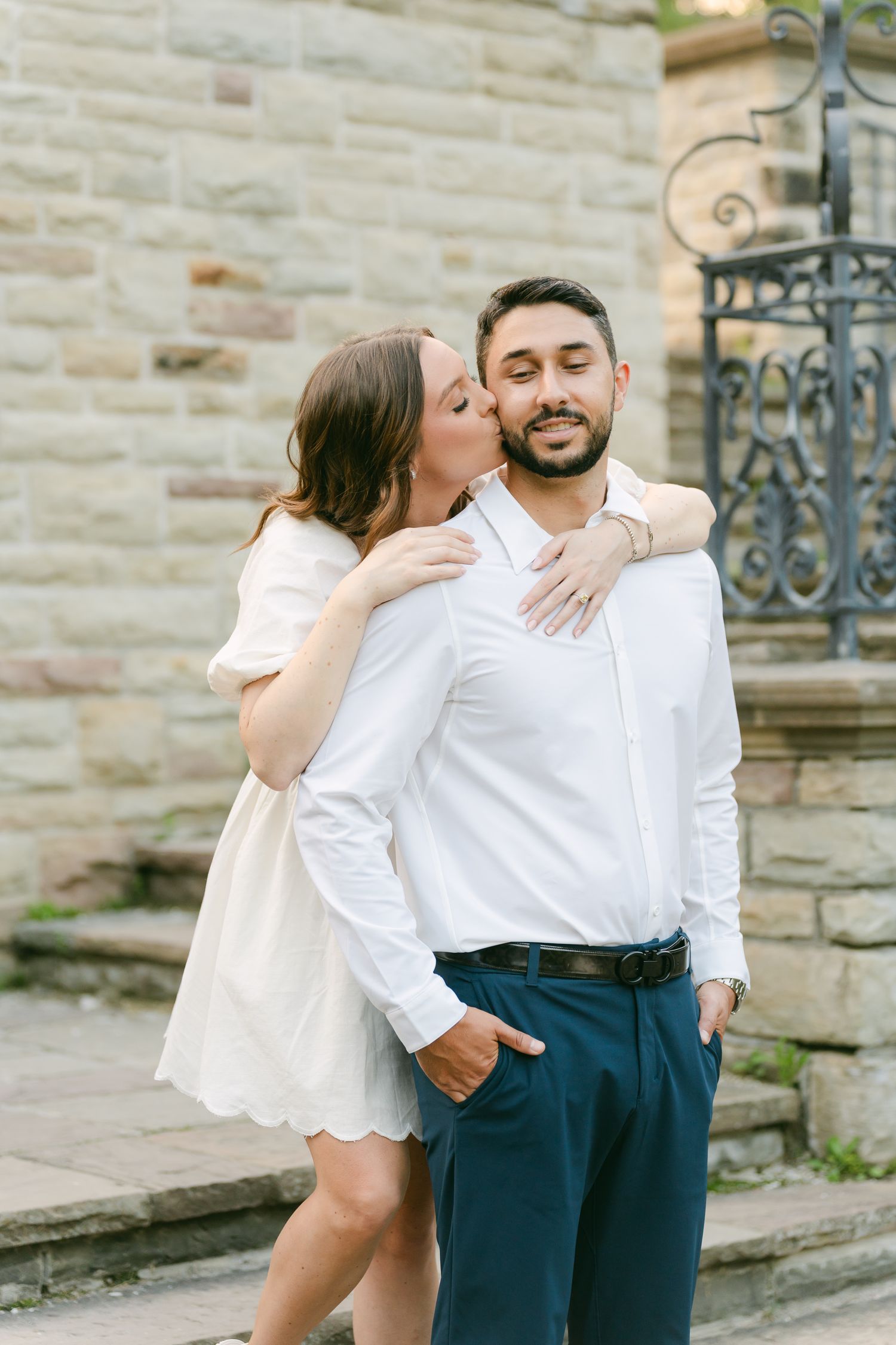 An affectionate moment captured between a couple in coordinated white outfits on historic stone steps.