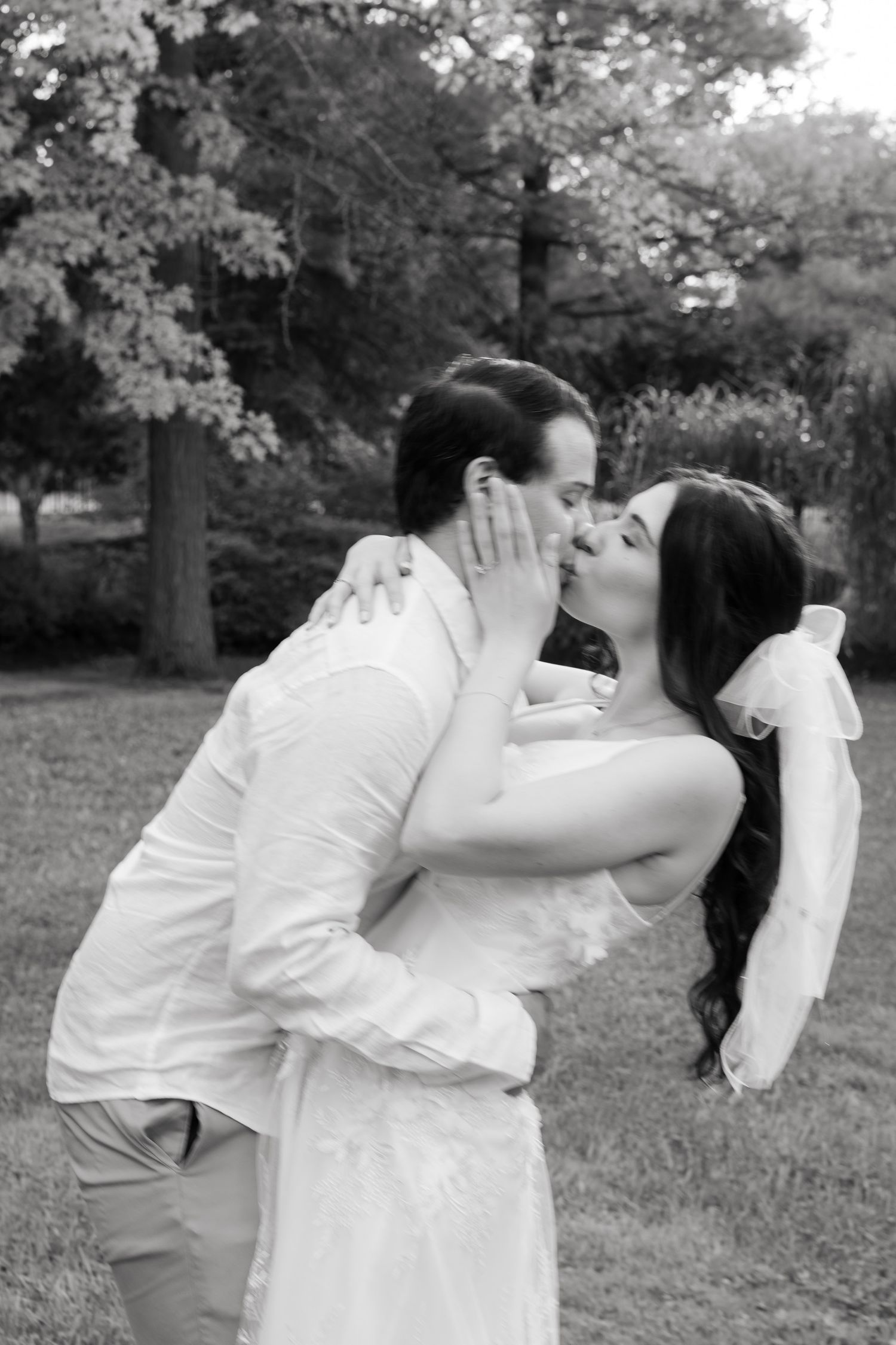 Intimate black and white portrait of a tender moment between newlyweds in a garden setting.