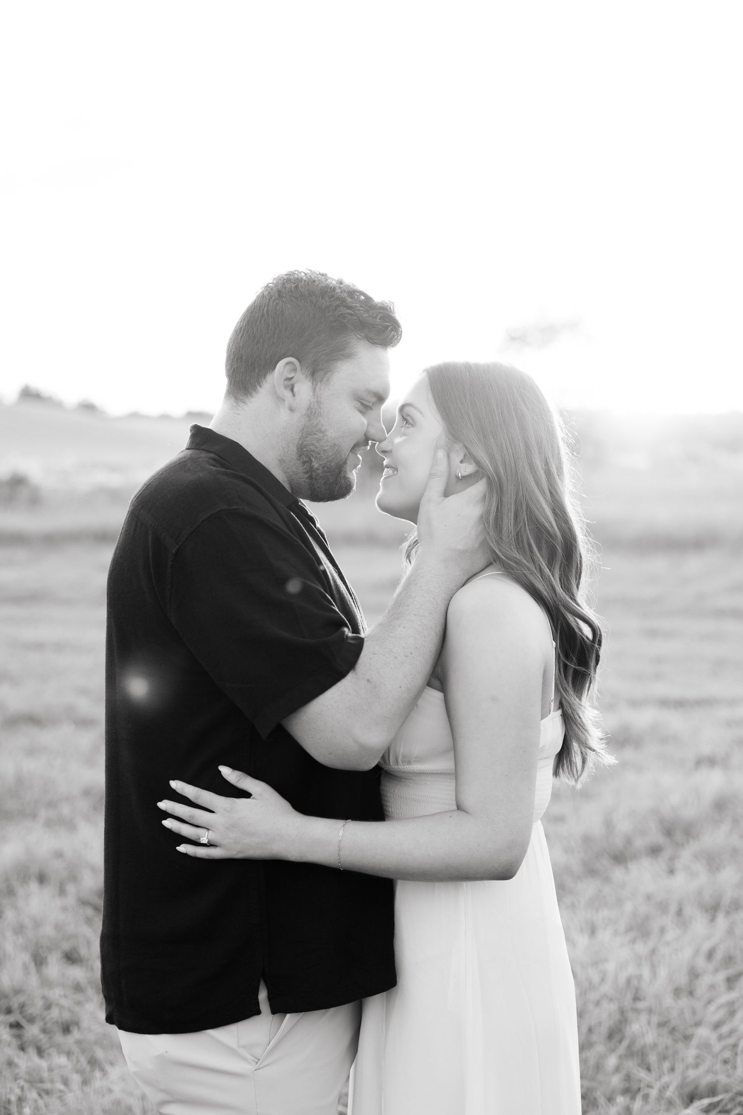 Black and white photo of couple in tender embrace during outdoor photoshoot.