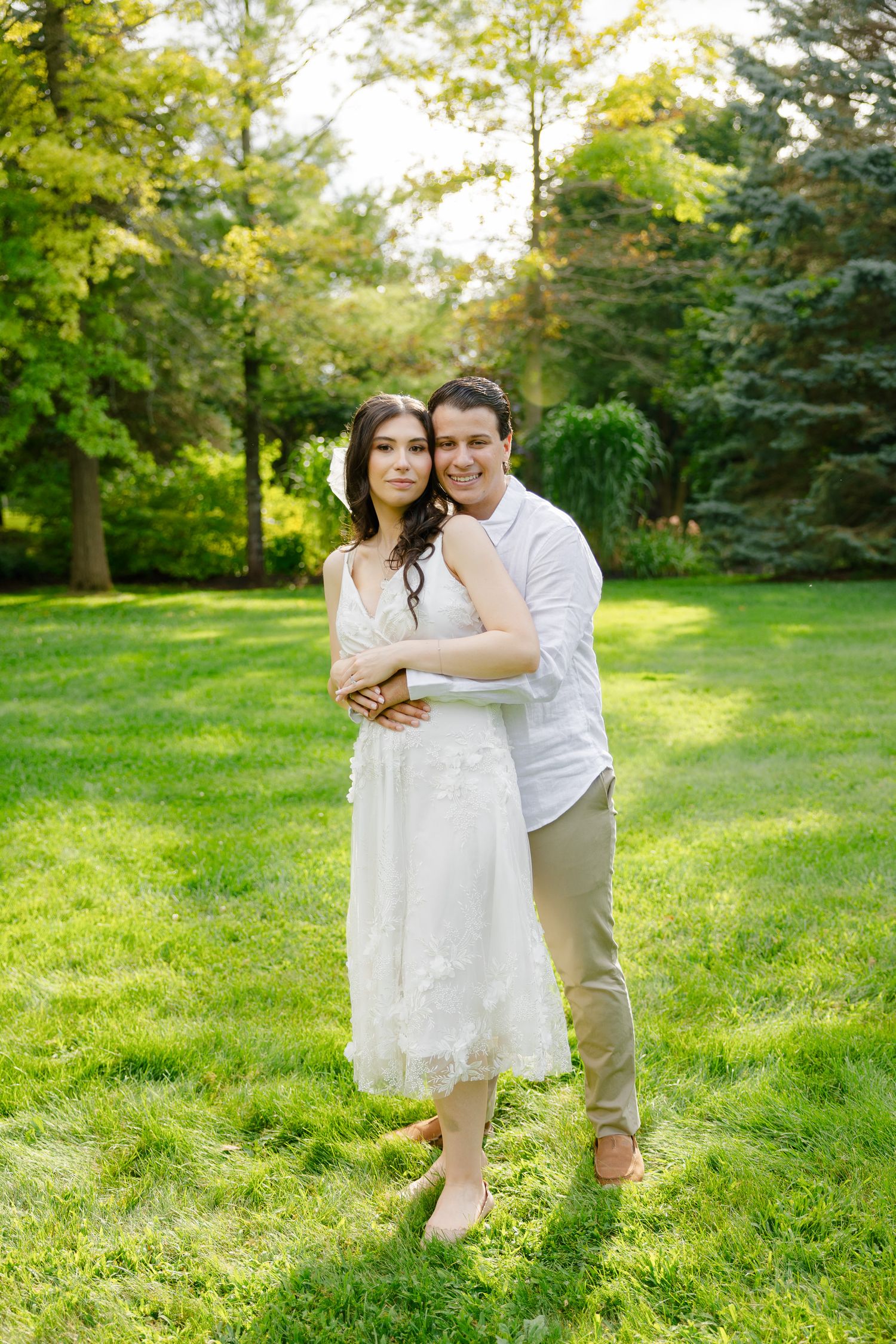 A romantic outdoor portrait in a sunlit garden with green foliage.