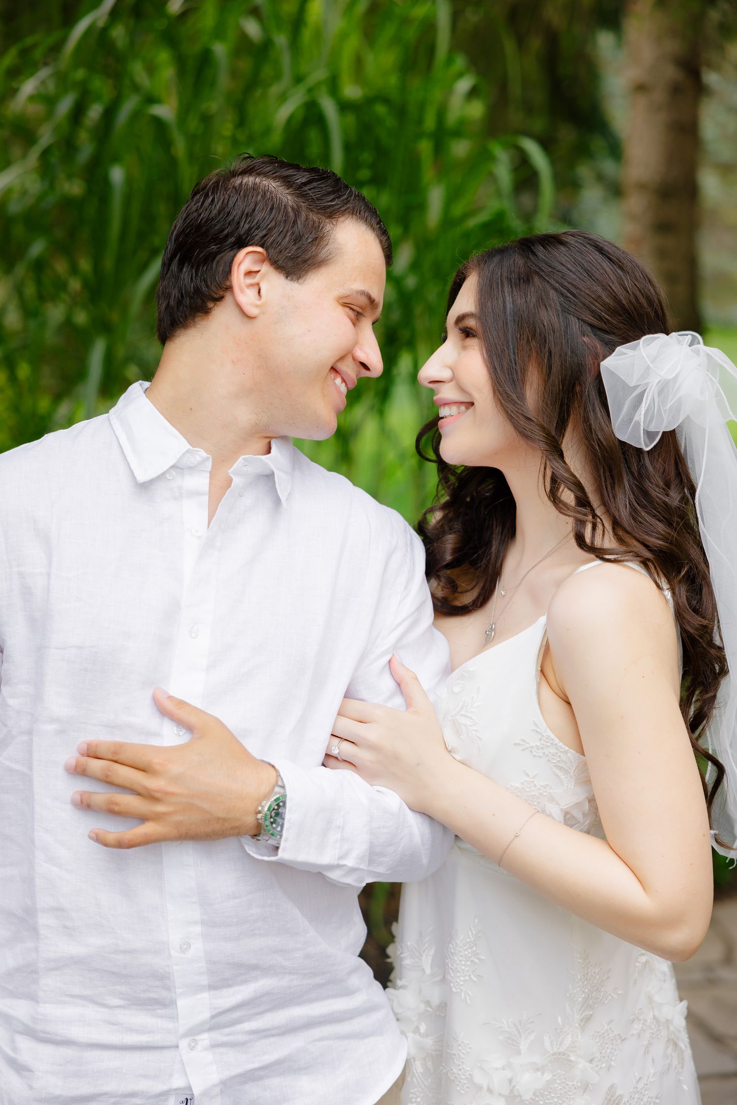 A candid moment of laughter between a wedding couple in a garden setting.