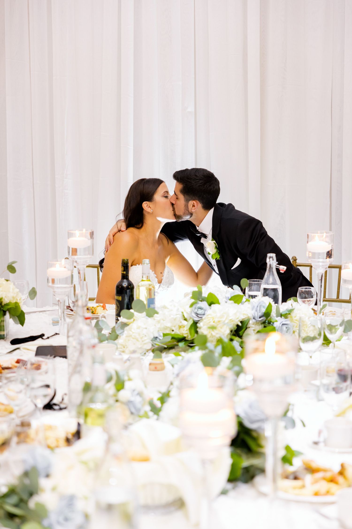 An intimate moment at the reception dinner table decorated with elegant white floral arrangements.