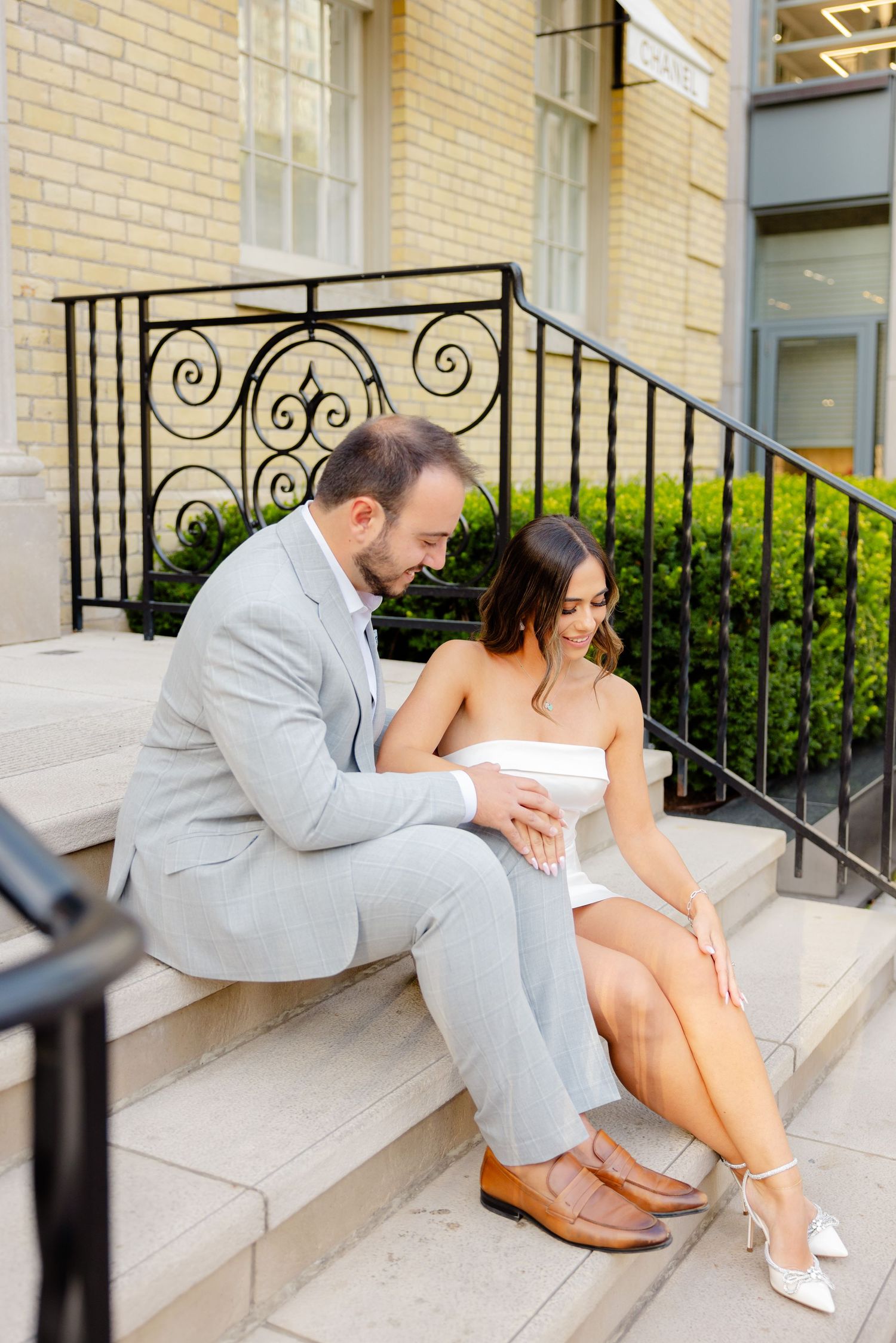 A romantic moment captured on the stone steps of a Chanel boutique with decorative iron railings.