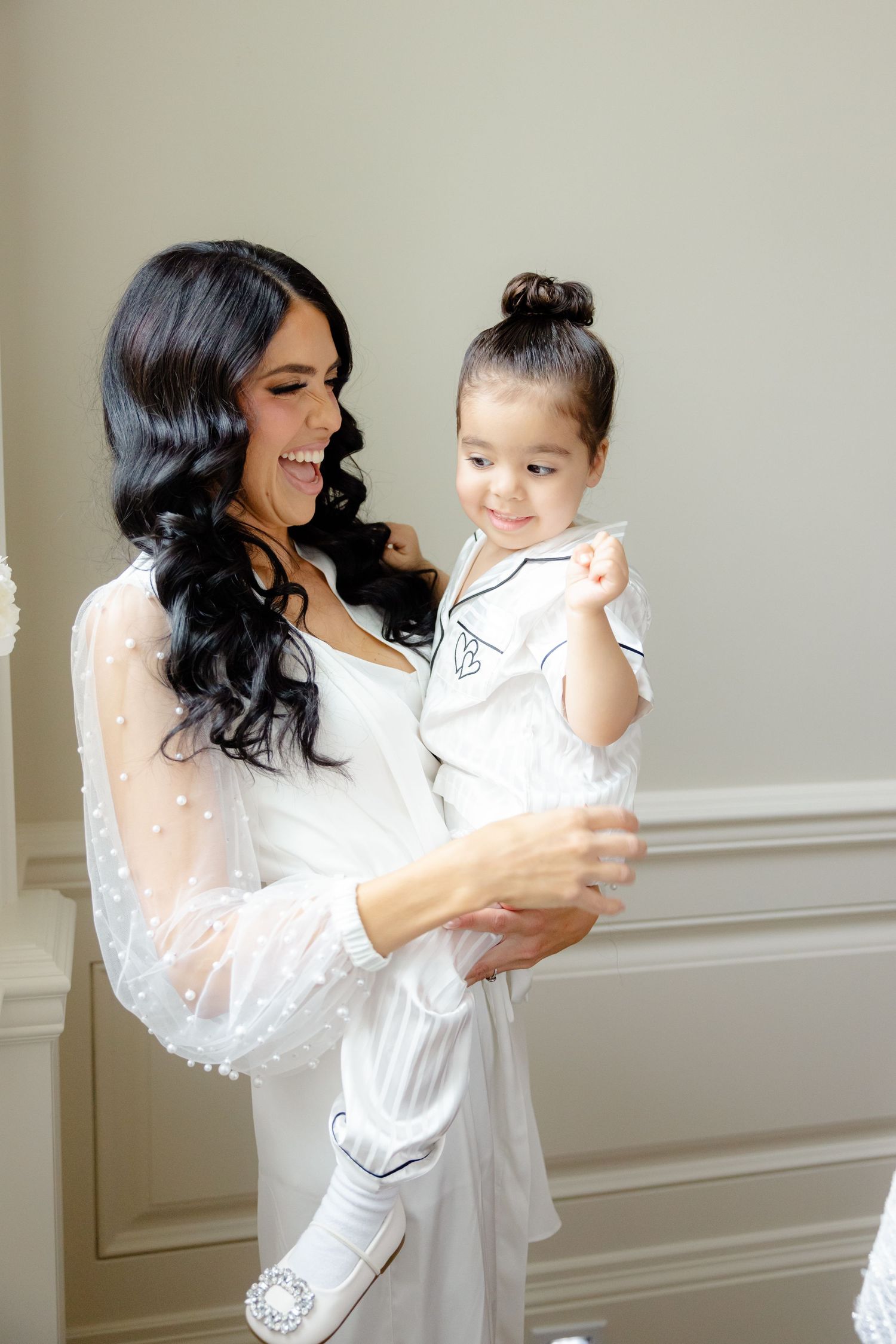 Sweet moment shared in a sunlit room with white lace robes and elegant decor.